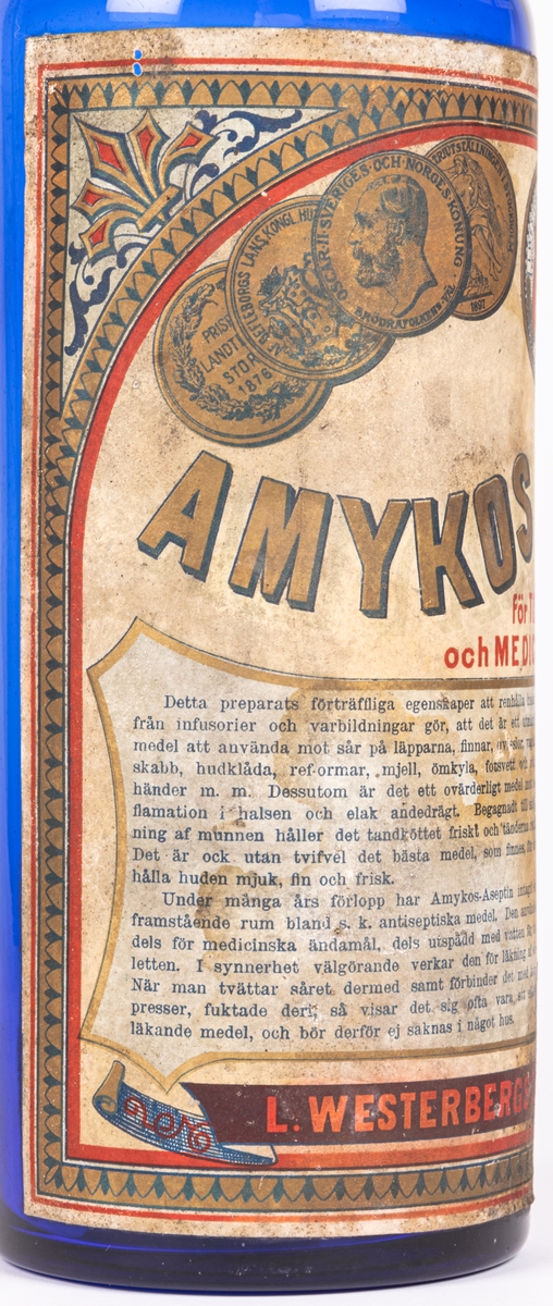 Blå glasflaska med klistrad pappersetikett:
Amykos Aseptin
L. Westerbergs tekniska fabrik Gefle.