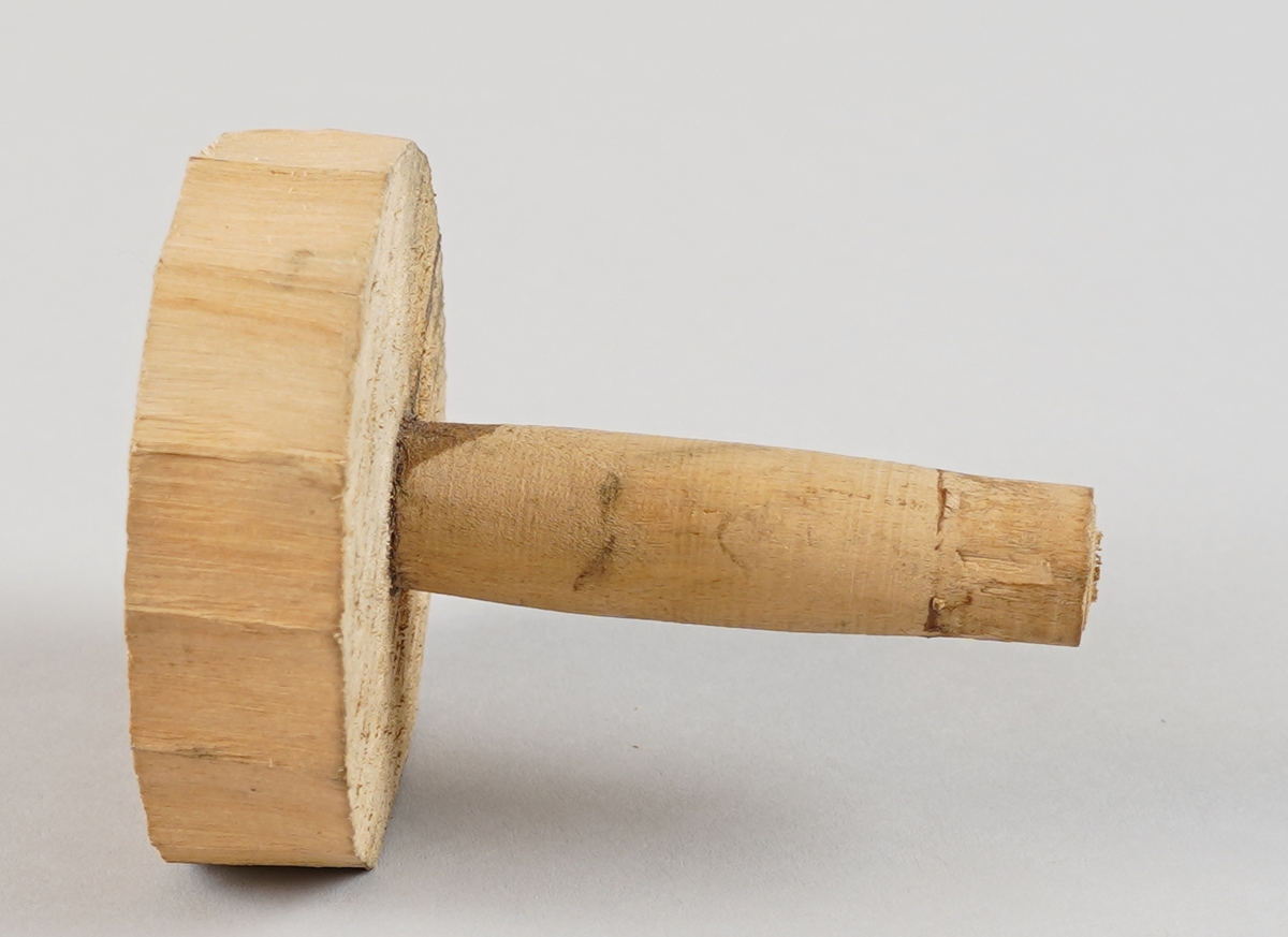 Emne til snelle (som er del av tein til hjulrokk) der eine klossen er borte.  Eit dreia stykkje er sett ned i ein tilnærma sirkelforma kloss i eine enda. Det er hol gjennom dei to delane i senter.