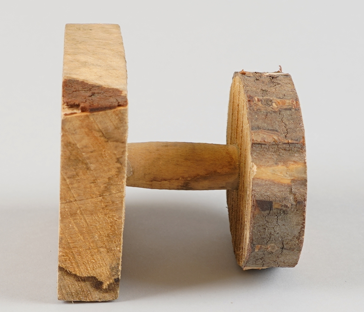 Emne til snelle (som er del av tein til hjulrokk). Truleg klar til dreiing. Eit dreia stykkje er sett ned i ein firekanta kloss (med rissa sirkel på oppsida) i eine enda og ein oval forma kloss med bark utanpå i andre enda (med rissa sirkel på nedsida). Det er hol gjennom alle tre delane i senter.