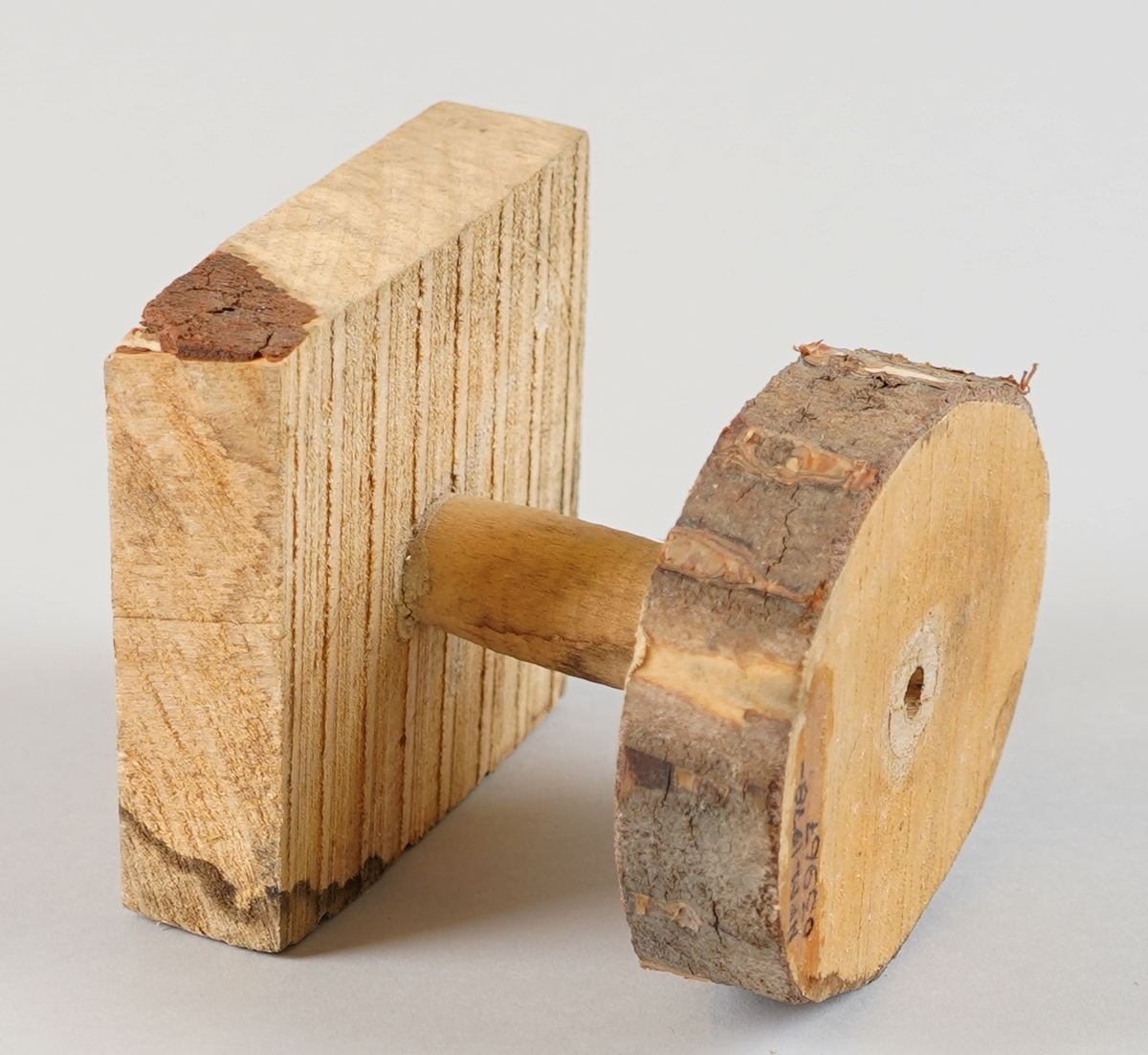 Emne til snelle (som er del av tein til hjulrokk). Truleg klar til dreiing. Eit dreia stykkje er sett ned i ein firekanta kloss (med rissa sirkel på oppsida) i eine enda og ein oval forma kloss med bark utanpå i andre enda (med rissa sirkel på nedsida). Det er hol gjennom alle tre delane i senter.