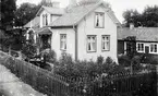 På verandan: t.h. C.G. Dahlstrand. Vid bordet Ernst Albin Pettersson med fru och sonen Gillis. Utanför verkstaden kopparslagaren Julius Berggren. Omkring år 1900.