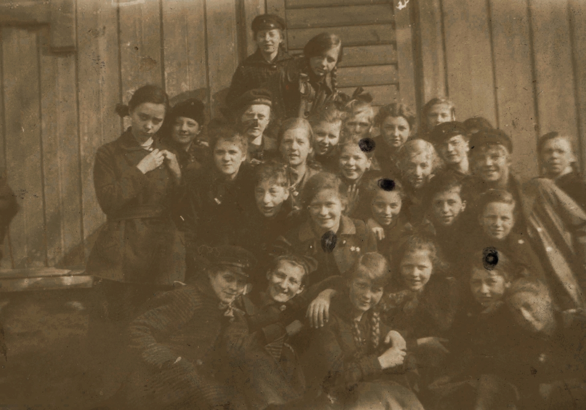 Portrettfotografi av ei skoleklasse utenfor et hus.