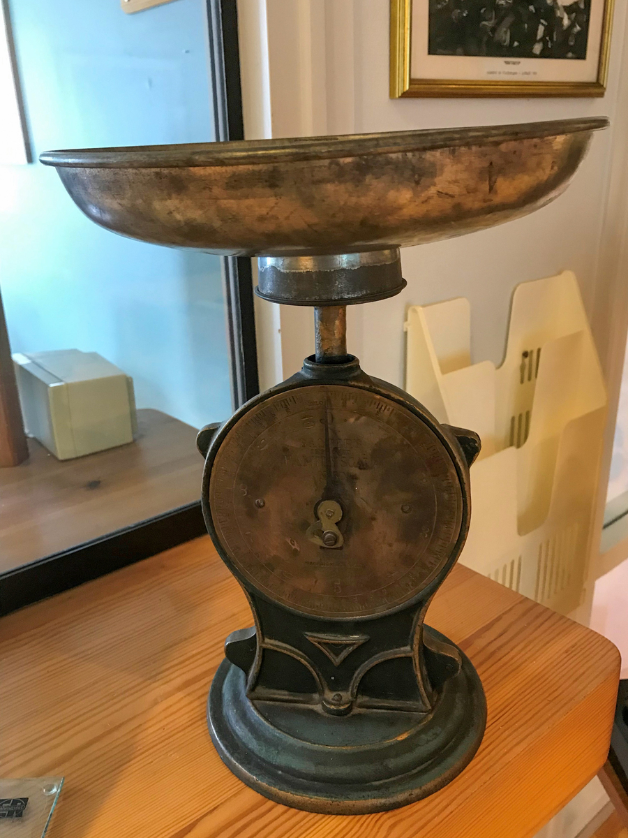 Vekt i mattlakkert støypegods med kilogram-skive i messing i front. Skåla på toppen er fast til vekta. 