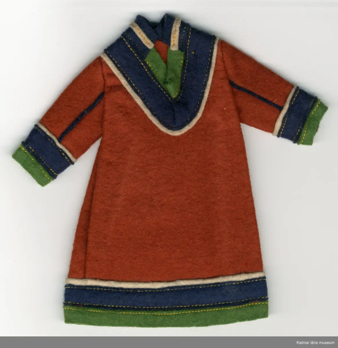 KLM 28082:292:1-3 Samekolt, dockkolt, 3 stycken, av textil, ylle. Lång kolt, utan öppning, brun, med grön, mörkblå och vit garnering. Nertill på ärm och koltens fåll, tygränder, lodräta, vit, mörkblå och grön, i nämnd ordning. Längs ärm, två blåa ränder i tyg, passepoalsydda. Krage, blå, hög i nacke, med vit tygrand, framtill, v-krage, i grönt, blått och vitt tyg. Del av samisk nationaldräkt.