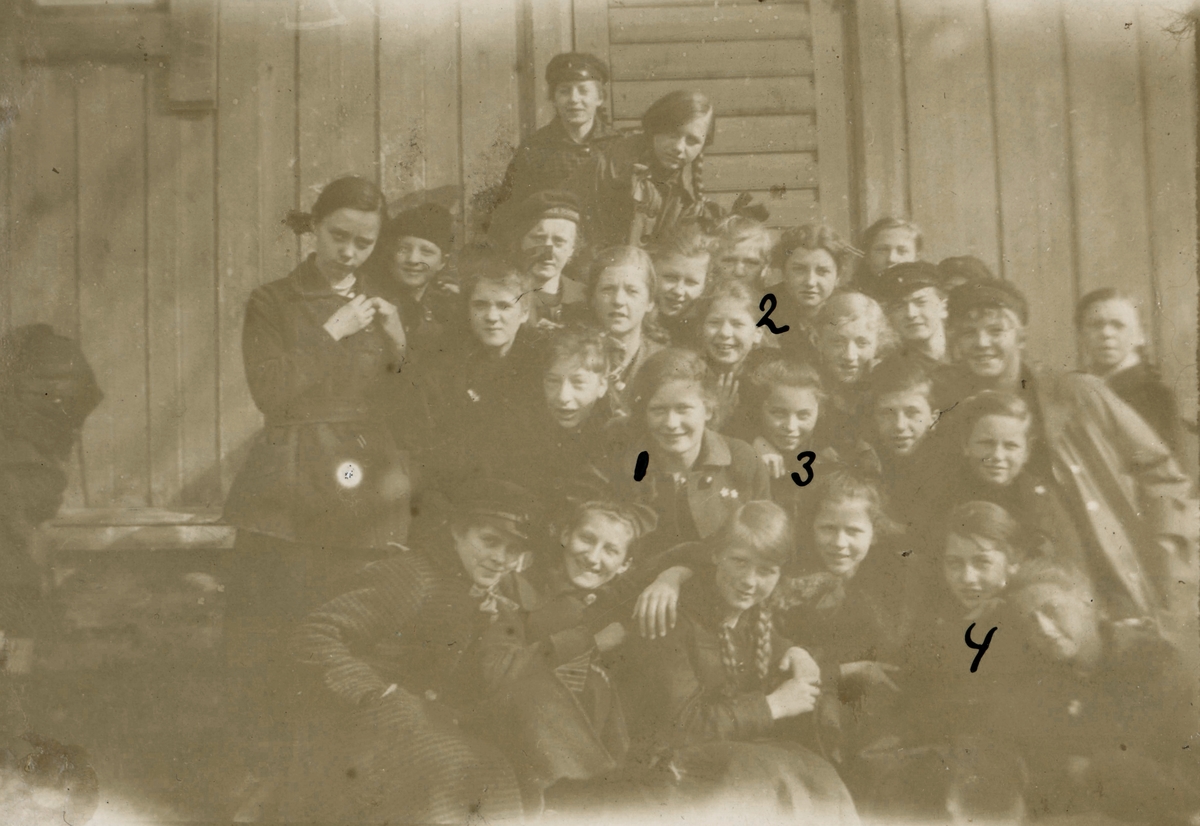 Portrettfotografi av ei skoleklasse utenfor et hus.