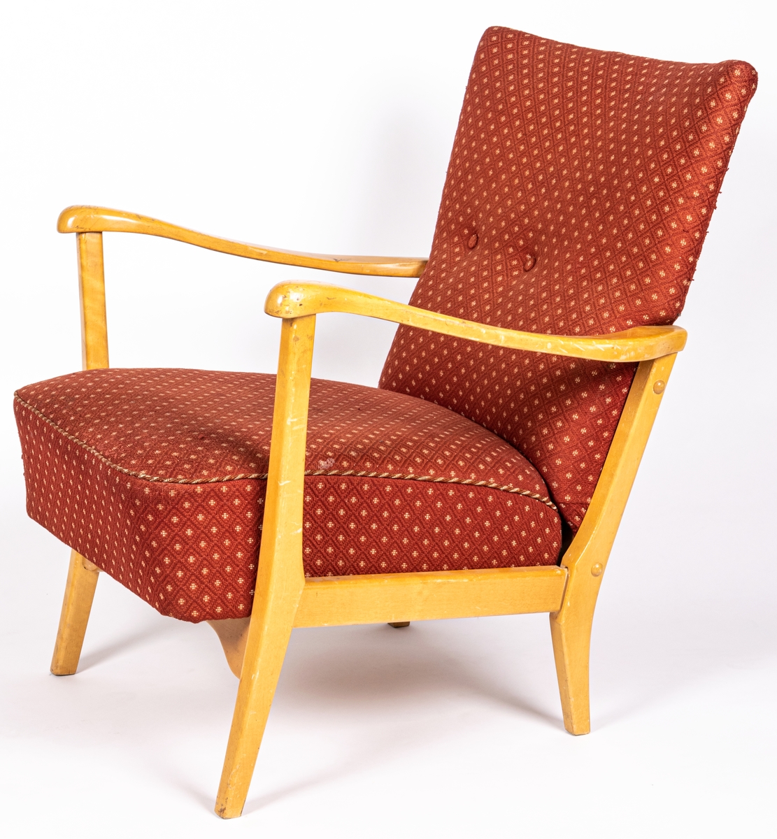 Katalogkort: Fåtölj. Ljust träslag i armstöd och ben. Sits och ryggstöd klädda med mönstervävt tyg. Varp: röd. Inslag: rett, vitt. Gåsögonliknande mönster. Sitsens kant, kantad med snodd i rött och vitt. På stolsryggens framsida fanns ursprungligen 3 textilklädda knappar, varav en saknas.

h 80cm, b 66cm, dj 77cm