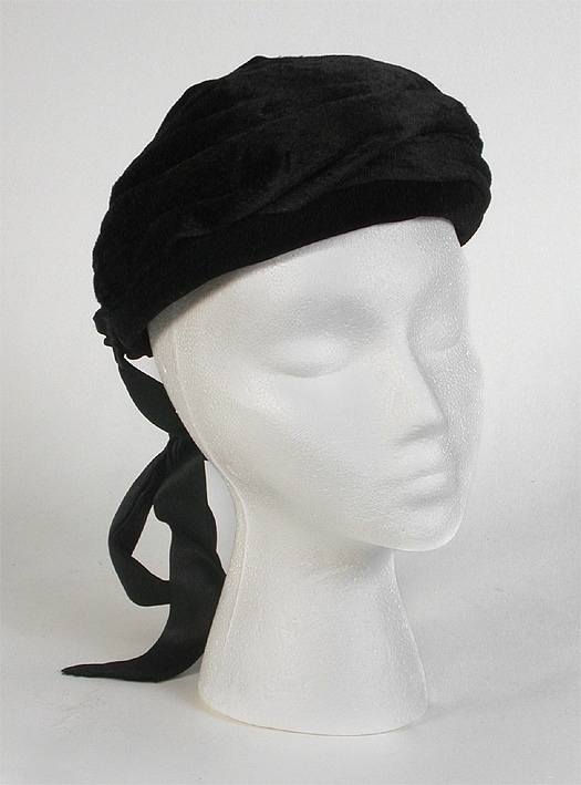 Av svart sammet med två 550 mm långa , svarta knytband av siden bak jämte svart resårband. 
Mått: 113 x 135 mm.