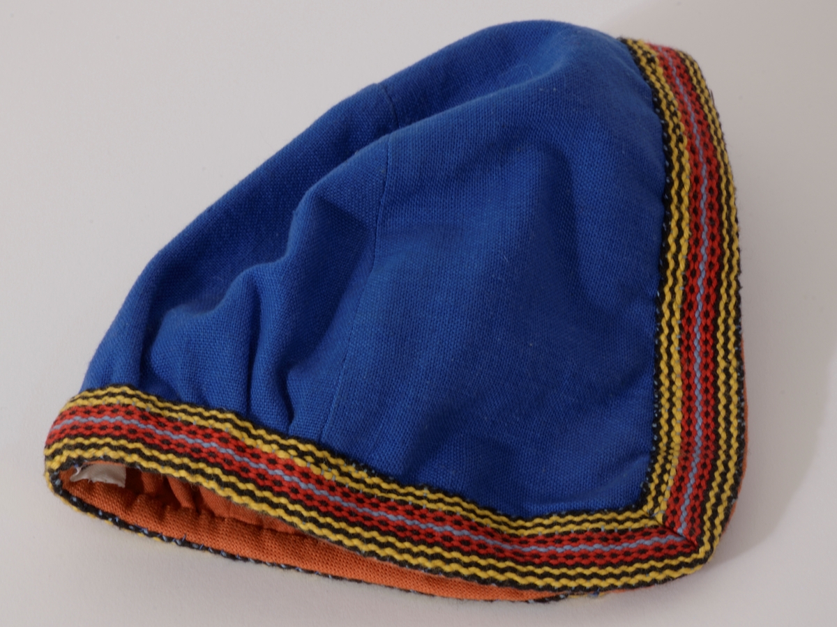 Vestfoldbunad 1932 modell, bomull. Stakk: Maljer med masker og tvunnet snor, flerfargede bånd om ermer, hals og skjørt, belte med  sirkelformet sølvspenne til å hekte, gravert dekor.  Forkle, litt nedsydde legg i livet, flettet rødbrun snor med dusk i endene, mønstervevd bord i gult/brunt nede.  Lue, D-form, bakstykket rynket nede, kantet med bånd, rødbrunt for.