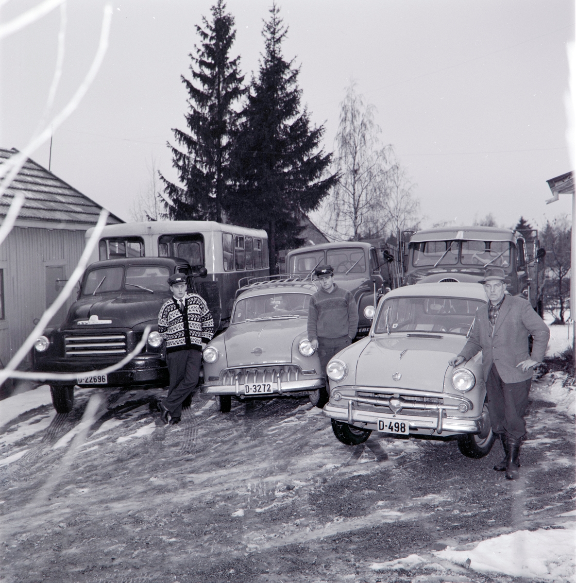 Foto bestilt av Keddell og Bommen A/S, Trading smøreoljer. Reklame opptak av lastebilene og bilene til J. Pettersen. Fra gårdstunet. 3 lastebiler og 2 personbiler.

Bak står det en Magirus Deutz Saturn og en Magirus Deutz Mercur. I front D-22696 , Volvo lastebil, med buss-kasse på lasteplanet. D-3272, Opel person bil og D-498 ukjent.