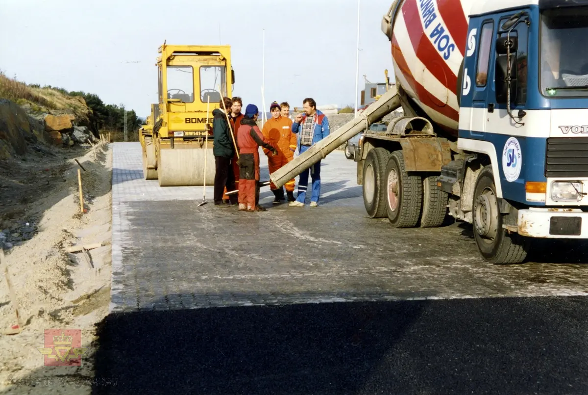 Rennfastutbyggingen - forsøksfelt med belegningsstein og betongforsterket asfalt på Harestad, ca. 1990. Ved Byfjordtunnelen. På bildet en Volvo betongbil og en vegvals.