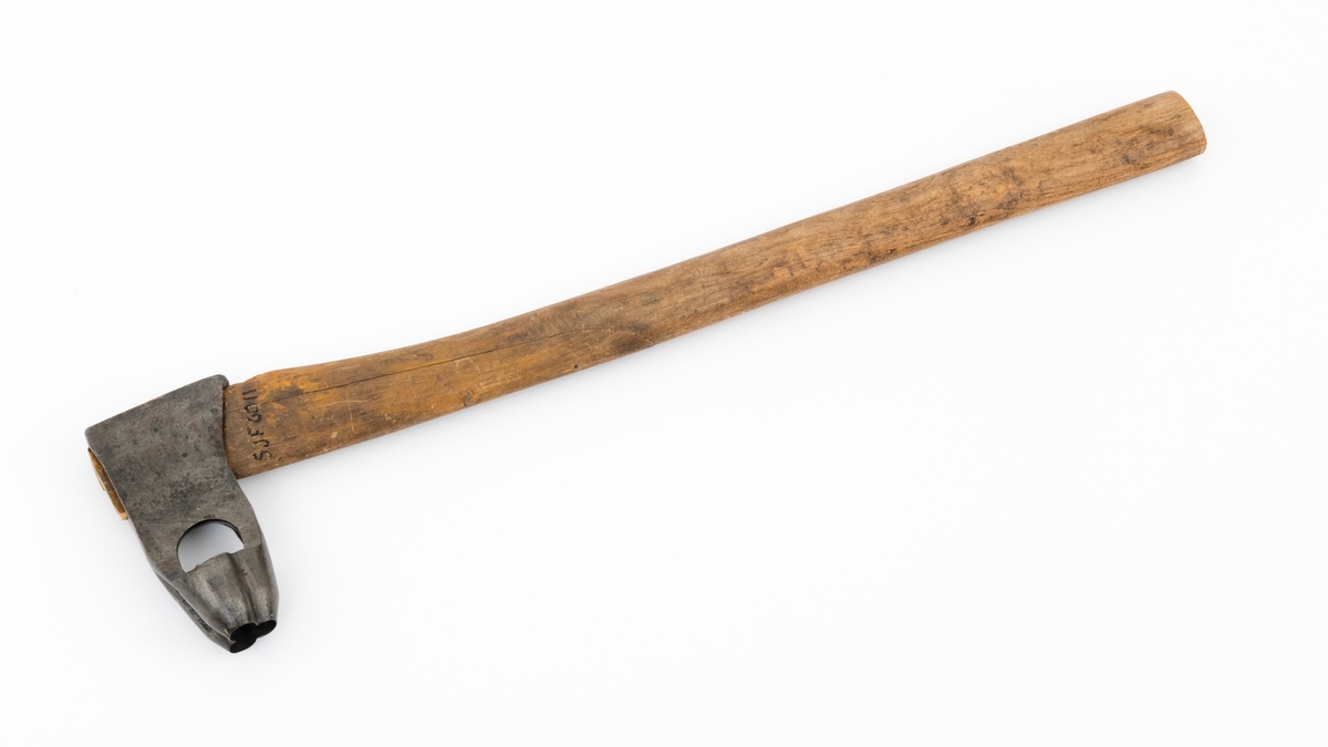 Merkeøks med ubehandlet askeskaft. Øksebladet er 13,8 centimeter høyt fra egg til nakke, og det noenlunde rektangulære nakkepartiet (hammeren) måler 7,6 X 2,7 centimeter. Øyet (skafthullet) er 4,3 centimeter høyt og opptil 1,5 centimeter bredt i forkant, noe romsligere i bakkant. På den nedre delen av bladgodset er det en U-formet utsparing som har fungert som sponrom for «merkedelen», et cirka 3,8 centimeter høyt element med profilert egg som er sveiset fast til «beina» (smeden kalte dem «stabler») på «U-en». Den profilerte eggen er fasslipt utvendig. Den er formet som et trefliket blad. Øverst på høyre side av øksebladet finner vi smeden stempel - «K. KNUDSEN MJØNDALEN» med to sirkulære avbildninger av medaljer produsenten sannsynligvis har høstet på utstillinger ved siden av. Dette tyder på at øksa kan være smidd av Karl Henrik Knudsen (1870-1956) eller eventuelt sønnen Oddmund Knudsen (1900-1983), som fortsatte å bruke farens stempel de første åra han drev smia. 

Skaftet er drøyt 61 centimeter langt (inkludert den delen som er skjult i øyet på øksa). Det er rett, og som økseskaft flest ganske flatt og bredt i den fremre enden og noe mer rundovalt baker. Forbindelsen mellom bladet og skaftet er gjort tettere og fastere ved hjelp av en trekile i skaftenden. Kilen er lysere i veden og nyere enn skaftet for øvrig. Navnet til firmaet som fikk det tømmeret det kjøpte i Numedalslågens nedslagsfelt merket med denne øksa - «Norsk Impregneringsco» - er påført høyre skaftside med grov svart tusj. Denne bedriften lå i Larvik.  På merkekartet for Numedalslågen fra 1960 har denne øksa nummer 19, og den knyttes til Asbjørn Danielsens navn. Dette eksemplaret var det Lågen Tømmermåling i  Larvik som forvaltet.

Bladet later til å ha vært demontert og rustbehandlet etter at det kom til museet. Skaftet er sprukket. Dette er sannsynligvis en gammel skade.