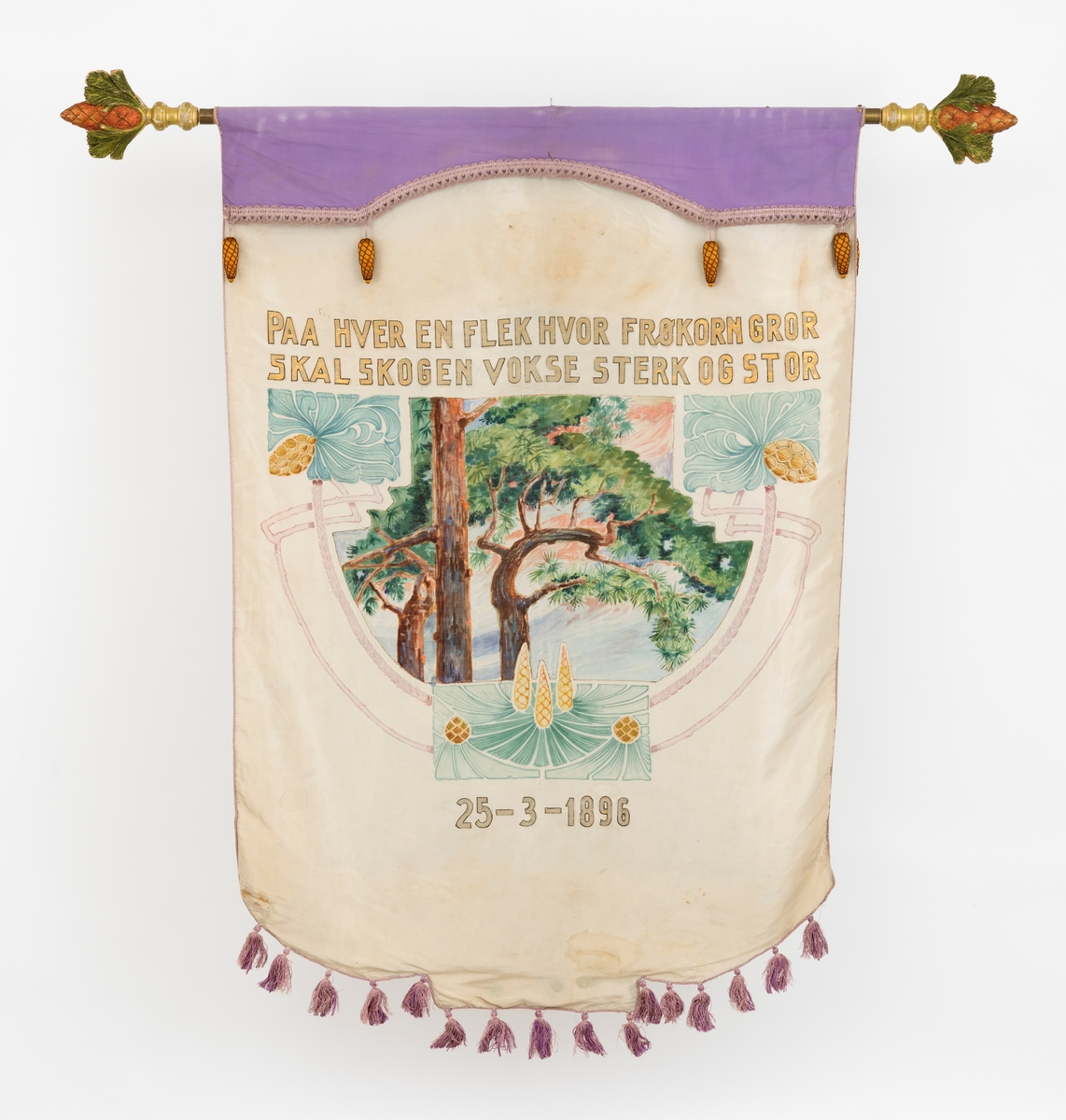 Fanen er malt på silke, det som ikke er malt er lilla i farven, snorene er også lilla. Motivene på fanen er fra skogen og har barn med. Dessuten står følgende inskripsjon: "Paa hver en flek hvor frøkorn gror skal skogen vokse sterk og stor", og på den andre siden: "Skogens venner"-  Som pynt på toppen av fanen og i hver ende på tverrstangen er det utskåret i tre og malt granbar med kongler.  Kongler av stoff henger også på selve fanen.  Gjenstanden består i alt av 8 deler (inkludert kasse). Se mer informasjon om hver enkelt del av gjenstanden se under gruppering.