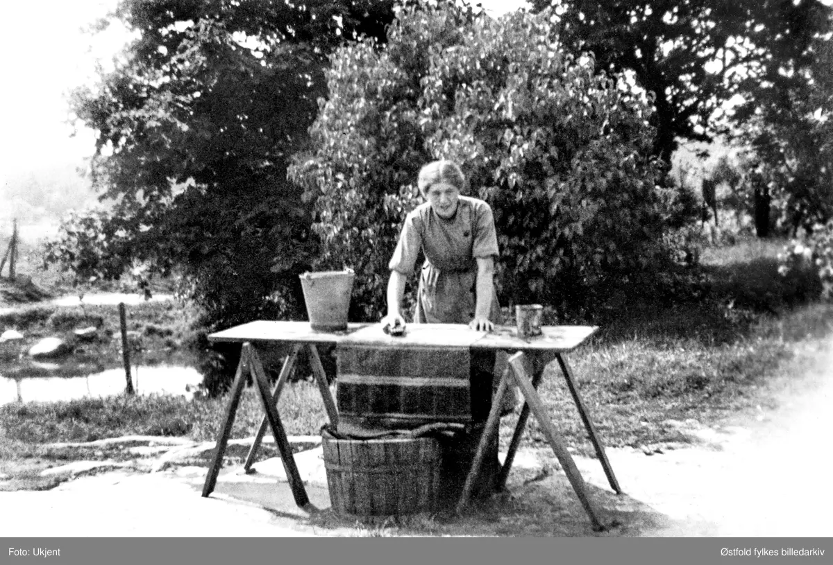 Adele Ringstad, f. Rostad (her ugift), skurer filleryer ved gårdsbrønnen på gården Rostad i Rolvsøy ca. 1935.