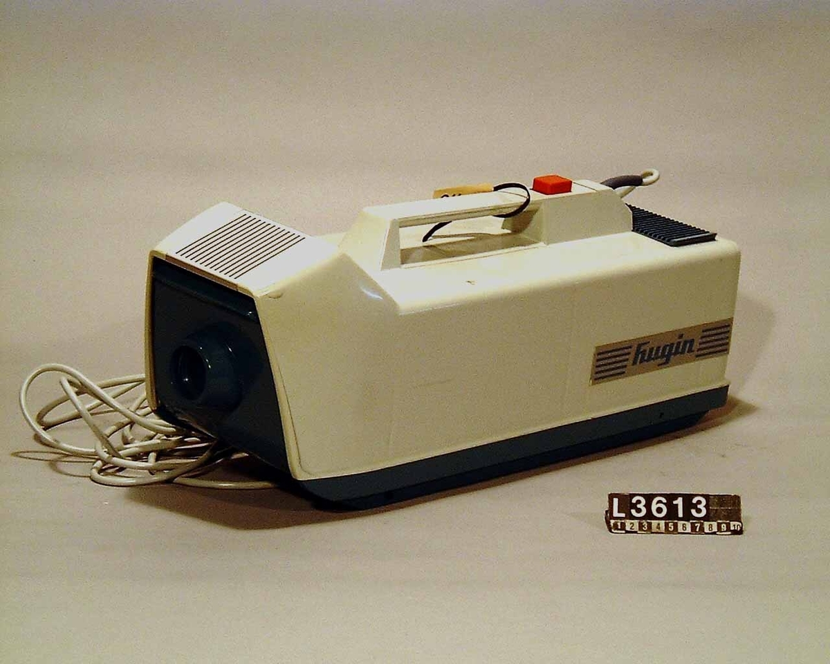 Dammsugare av märket Hugin helt i plast. Ovandelen är i ljusgrå plast, medan underrede och framlucka är i blå plast. Maskinen saknar bricka med tillverkninguppgifter. Slang, rör och munstycke saknas.
Tillbehör: Dammsugarpåsar.