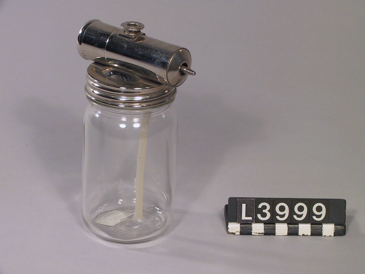 Vätskespridare där ovandelen är i kromad metall och behållaren är i klarglas.