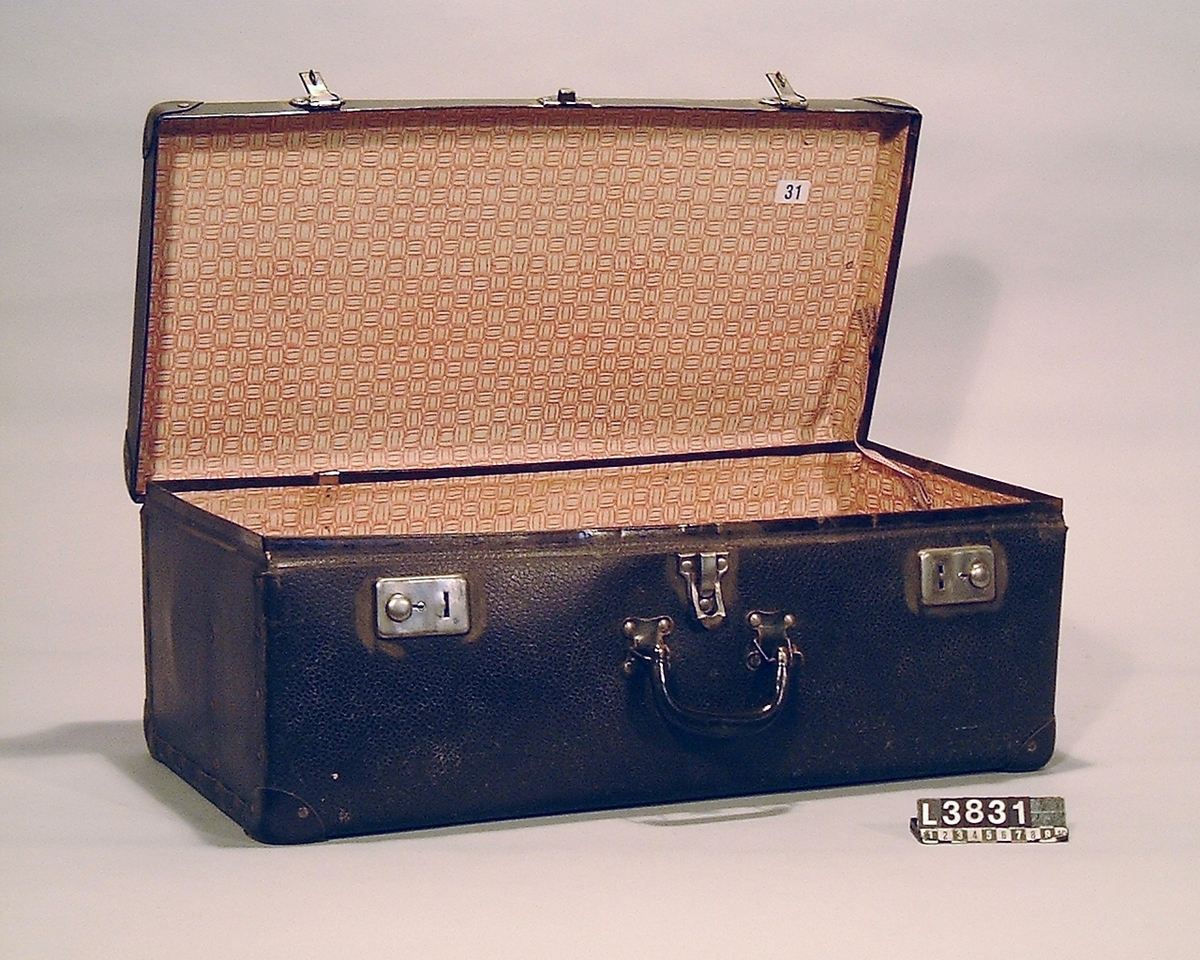 Cylinderdammsugare klädd i vinröd/flammig pegamoid. Fram och bakstycke samt medarna är i metall. Apparaten ligger i en koffert/väska. Under apparaten finns en etikett med Nr 31. Apparaten är alldrig använd, flera av tillbehören är inslagna i papper. Alla delar finns.