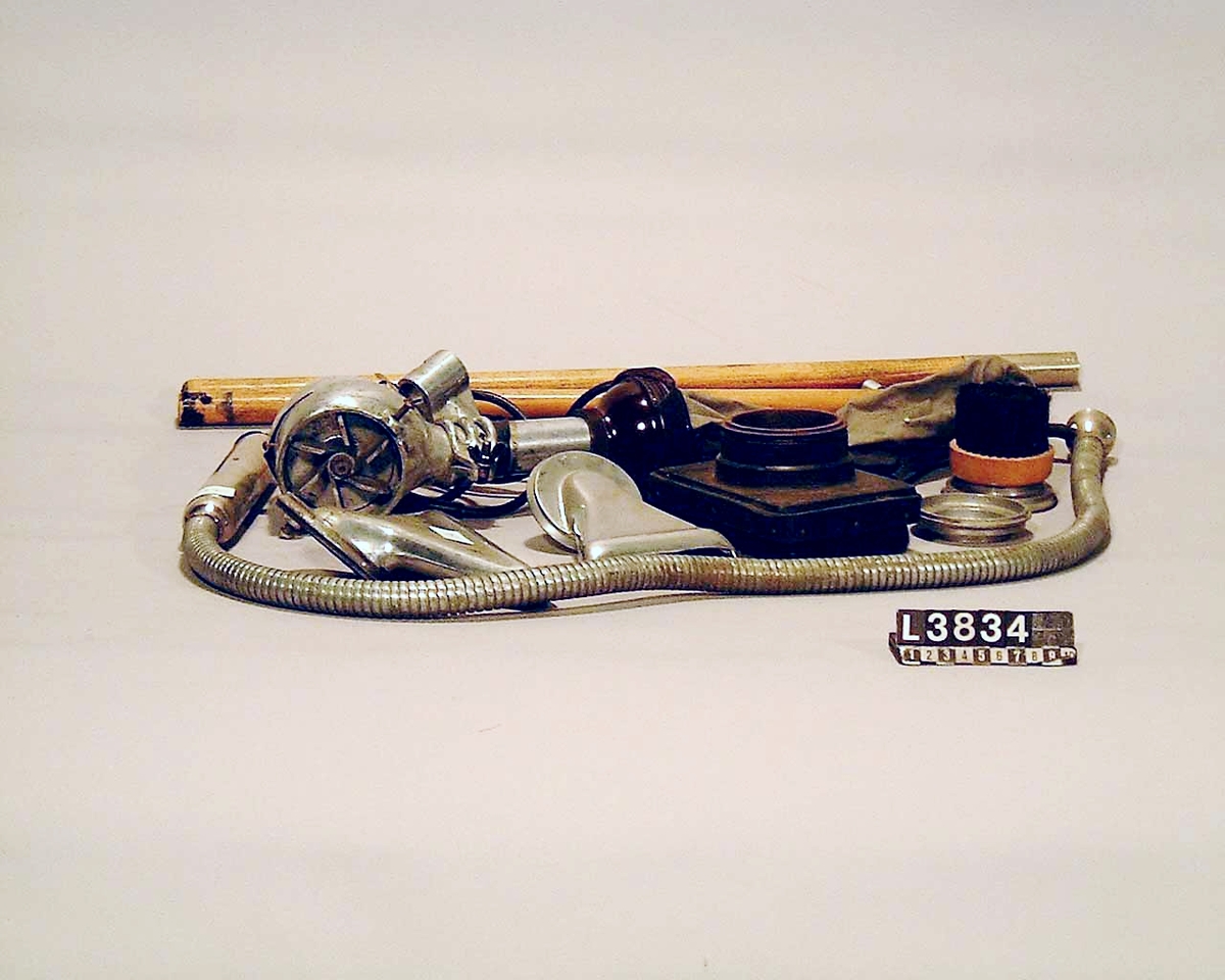 Skaftdammsugare i blankmetall, samtliga tillbehör i metall. Golvmunstycke är i järn värmebatteri för hårtork finns med.