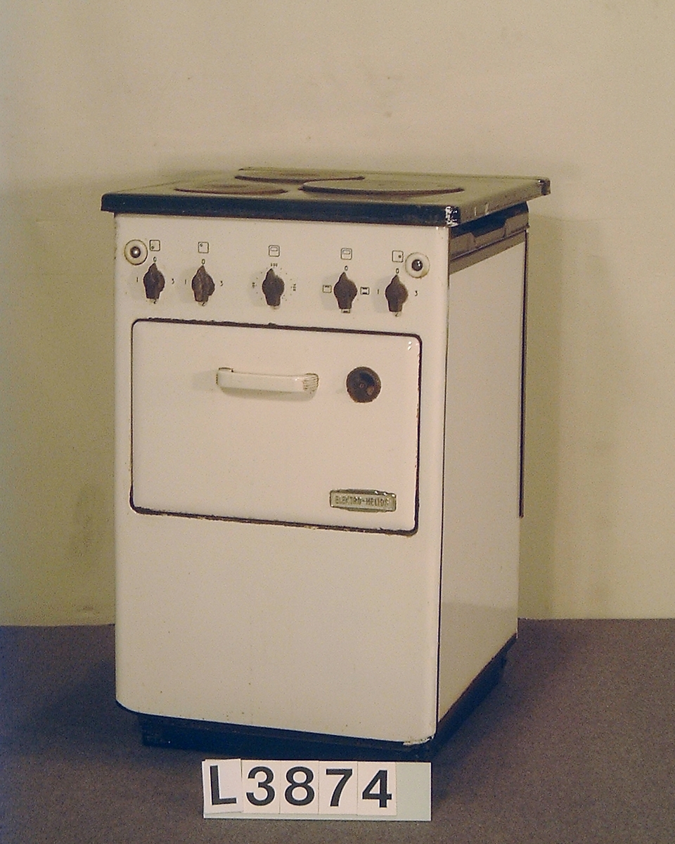 Smalspis med bredden 50 cm. Tre plattor och ugn. Fronten är emaljerad i bengult och den uppfällbara överhällen är emaljerad i svart. Spisen har inget värmeskåp. Spisen saknar vänster sidoplåt.