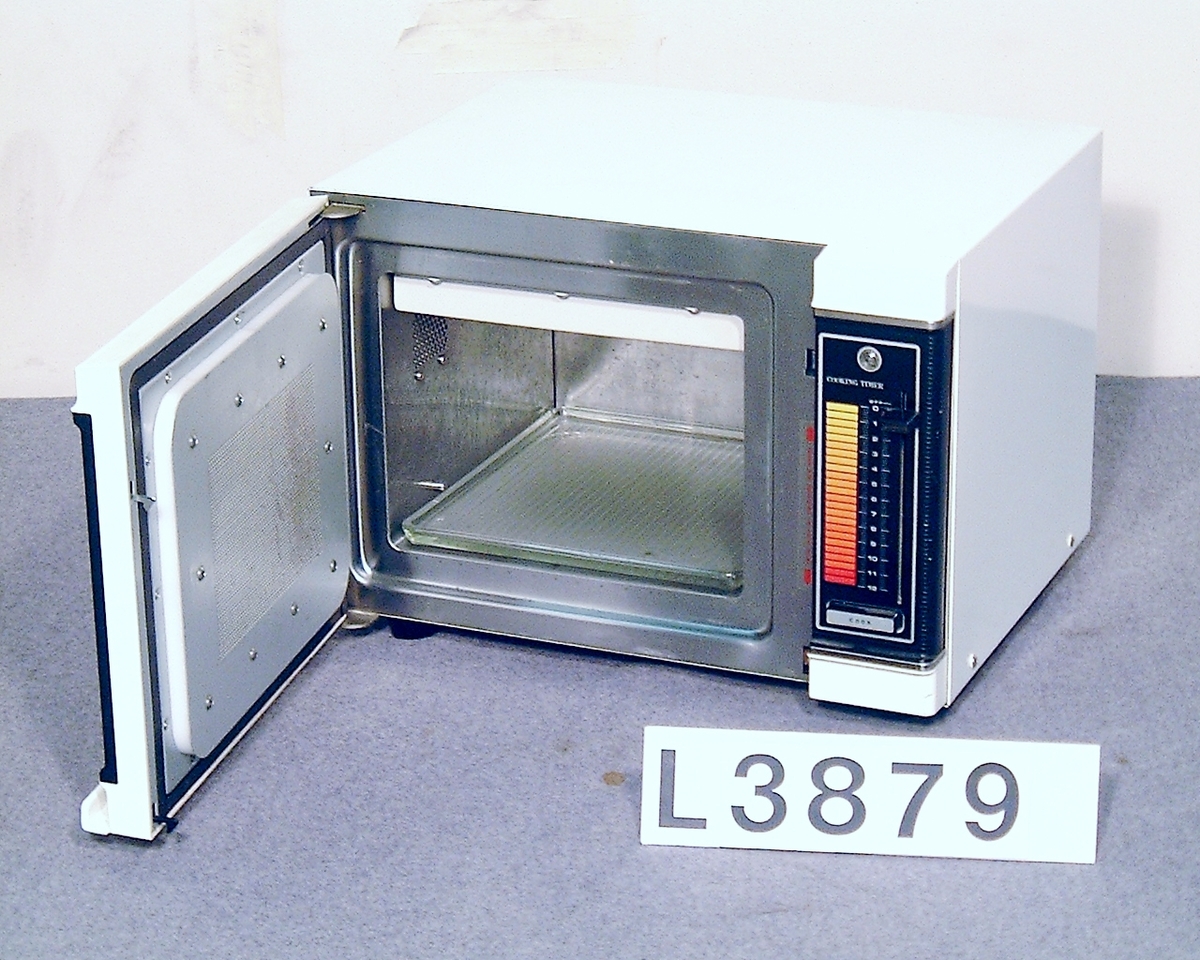 Mikrovågsugn, fyrkanig vit med svart frontlucka. Tidsinställning i form av termometer - skala med skjutvred. Startknapp och ett effektläge.