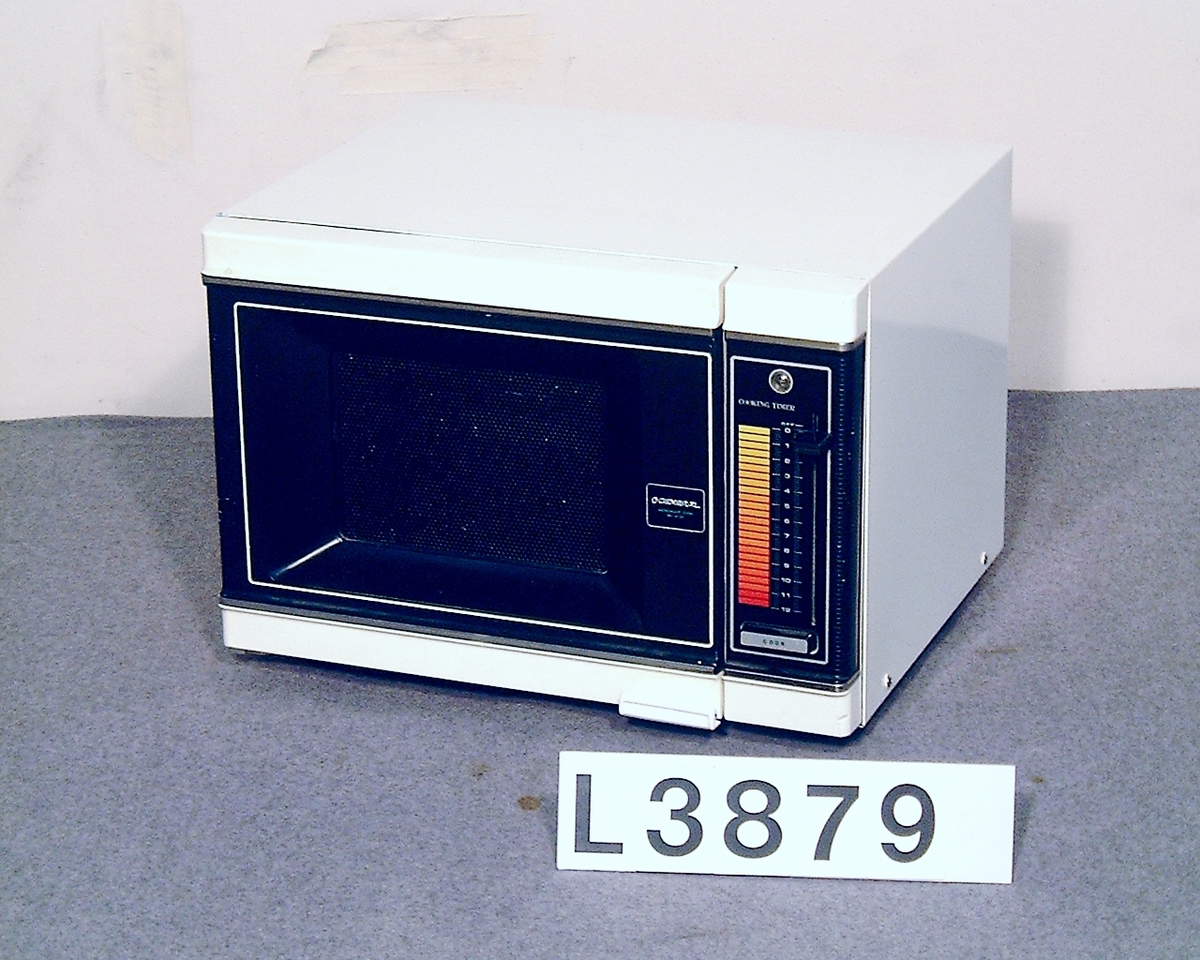 Mikrovågsugn, fyrkanig vit med svart frontlucka. Tidsinställning i form av termometer - skala med skjutvred. Startknapp och ett effektläge.