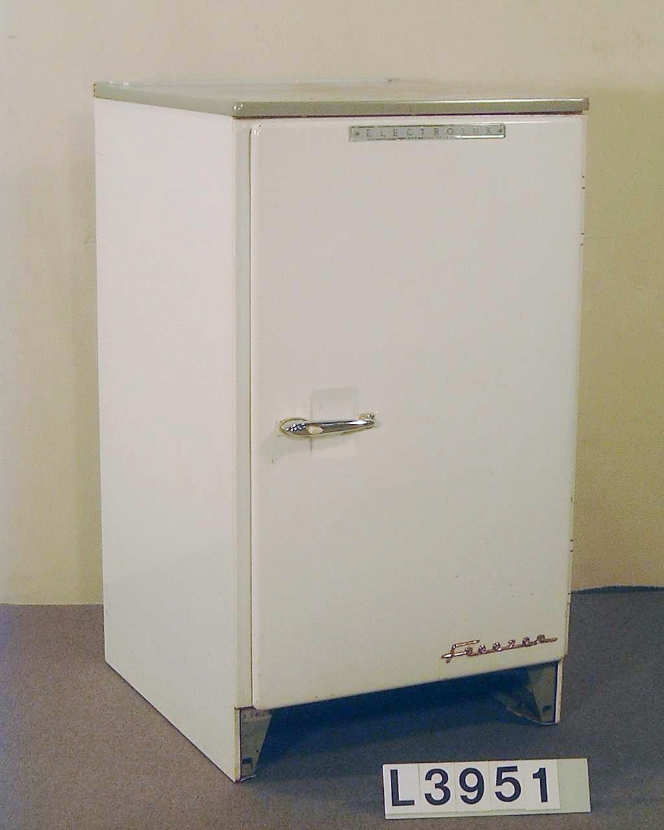 Kompressordrivet fristående frysskåp av Table Top typ. Frysen är lackerad i benvit färg och har en grå arbetsskiva ovanpå.