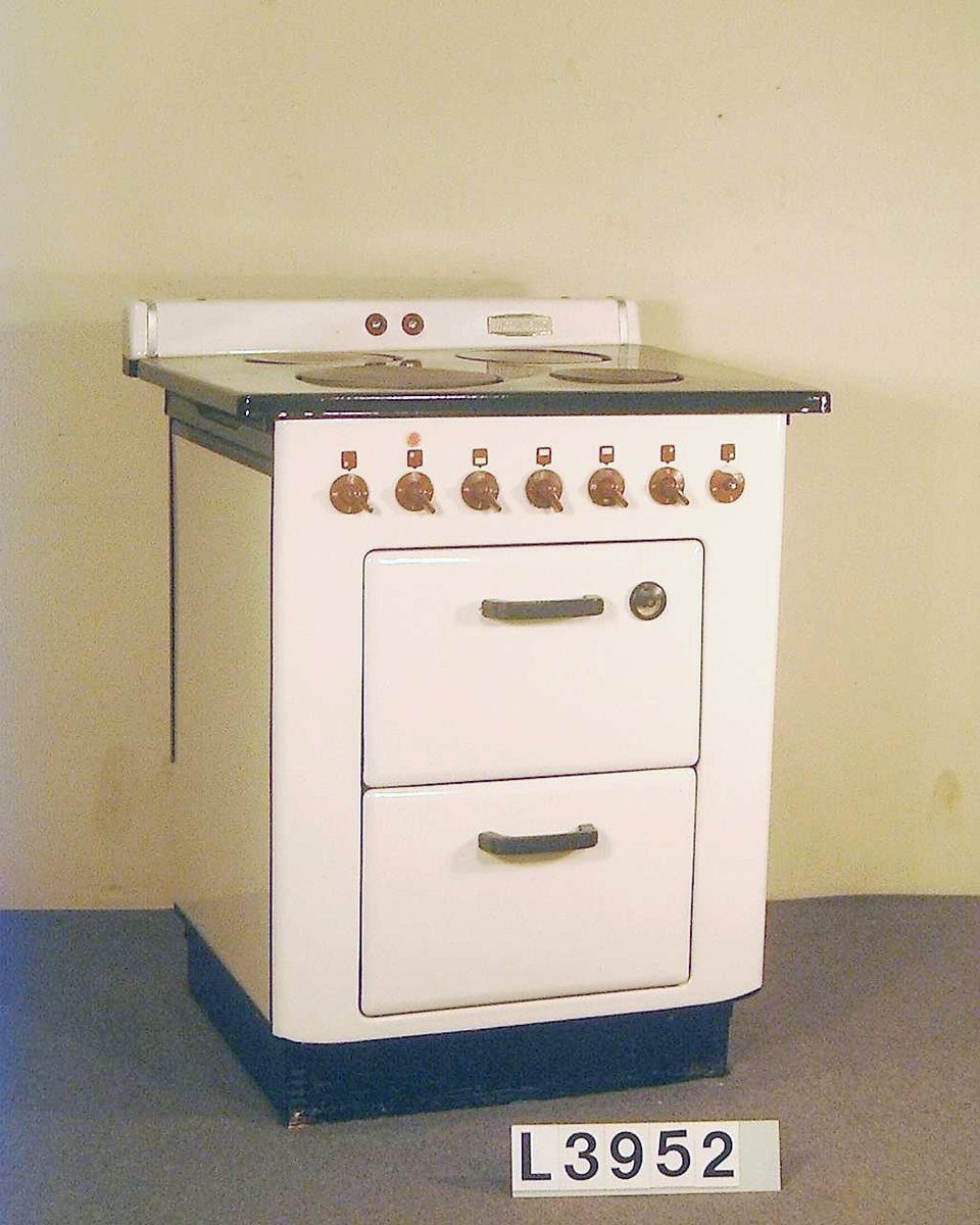 Elektrisk spis med emaljerad front i benvitt. Överhällen är emaljerad i svart. Spisen har ugn och värmeskåp. Strömställarna är i röd plast. Bak på överhällen sitter en panel med signallampor.