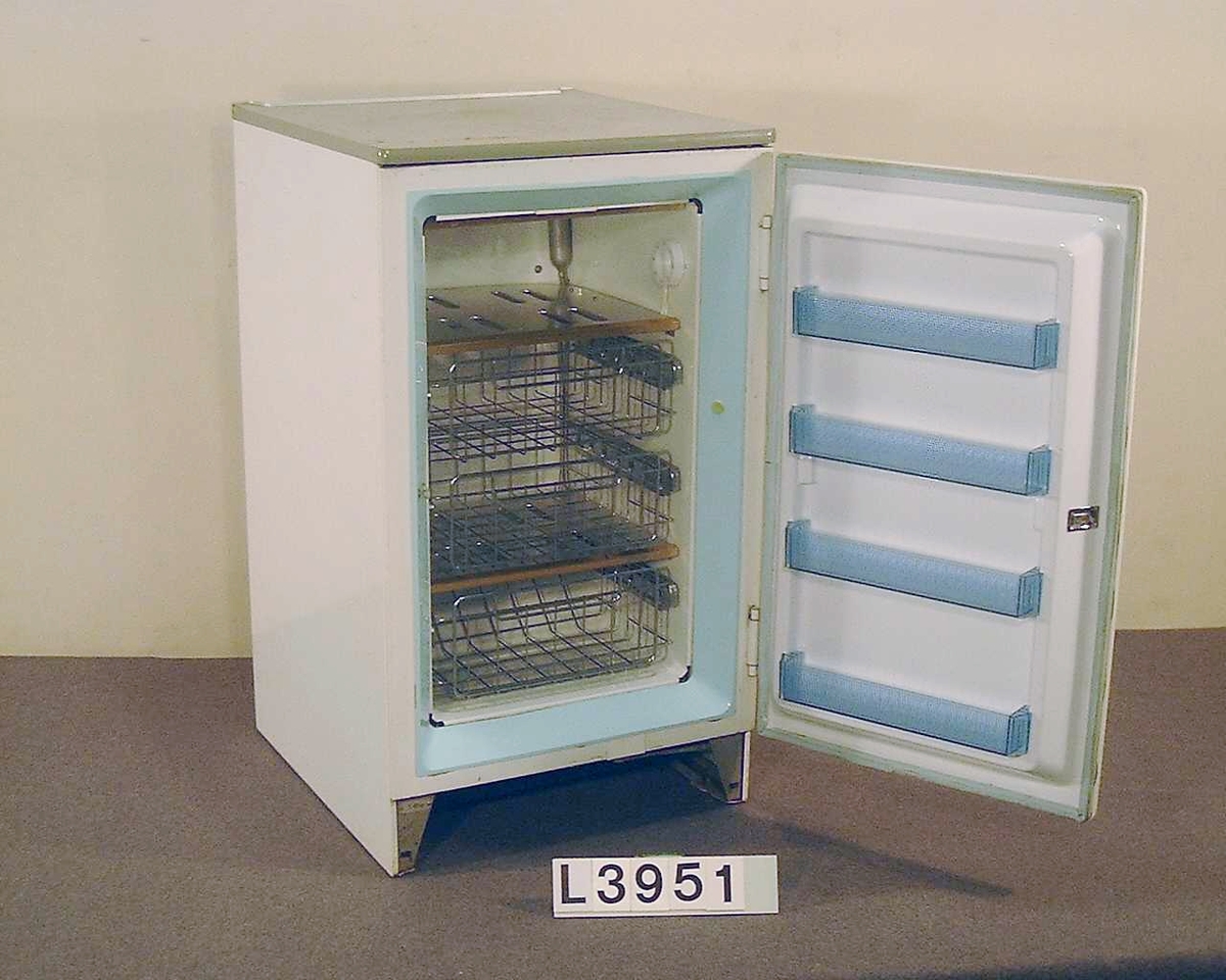 Kompressordrivet fristående frysskåp av Table Top typ. Frysen är lackerad i benvit färg och har en grå arbetsskiva ovanpå.