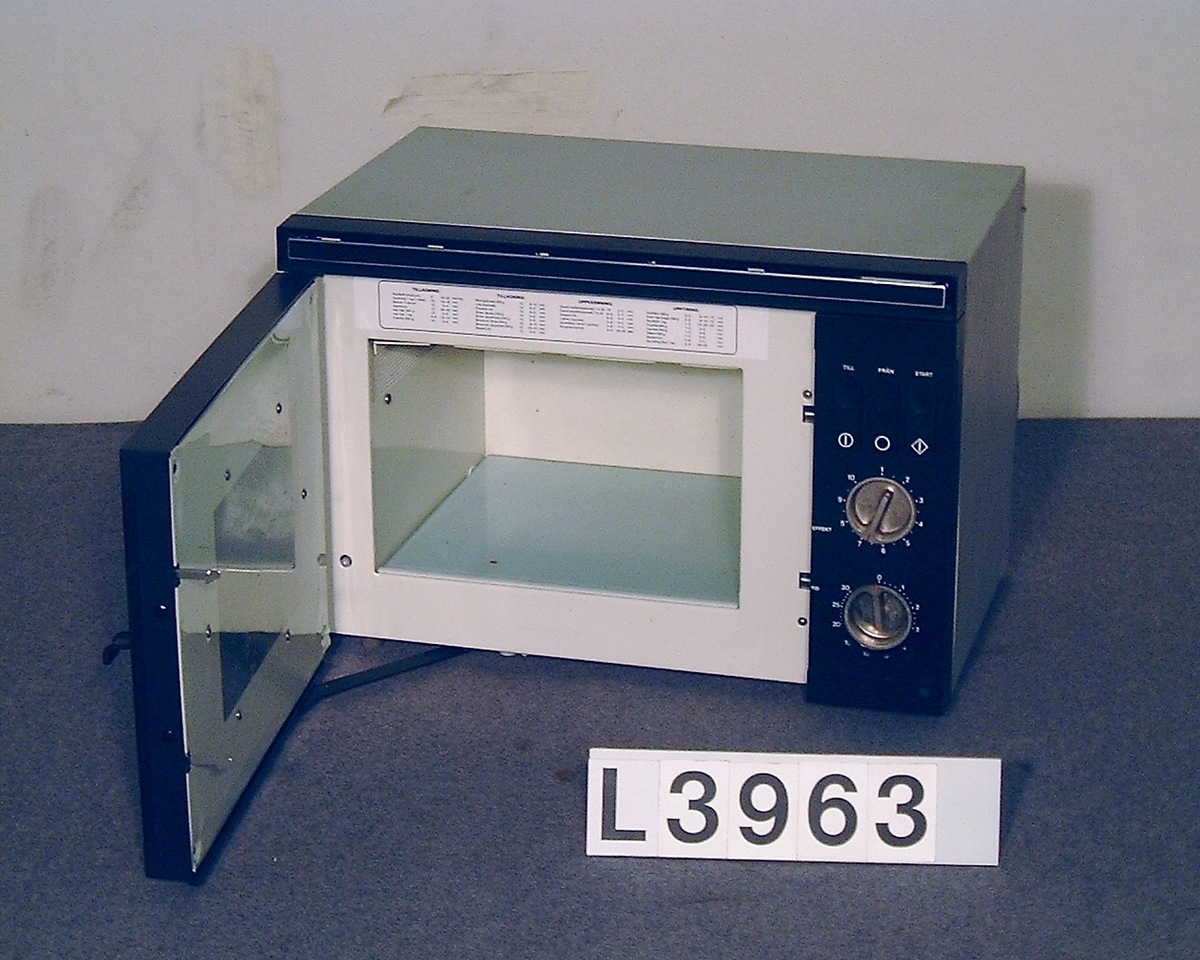 Mikrovågsugn med brun front av märket Elektro Helios. Infällda vred i blank metall för tid och effekt. Infällda tryckknappar för start, samt on & off.