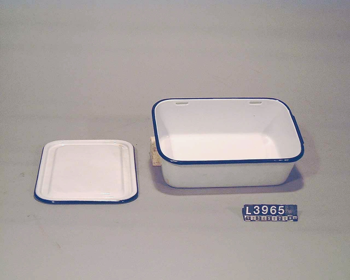 Vitemaljerad låda med blåa kanter och lock för matförvaring. Lådan har ett mått på  35 x 12 cm.
