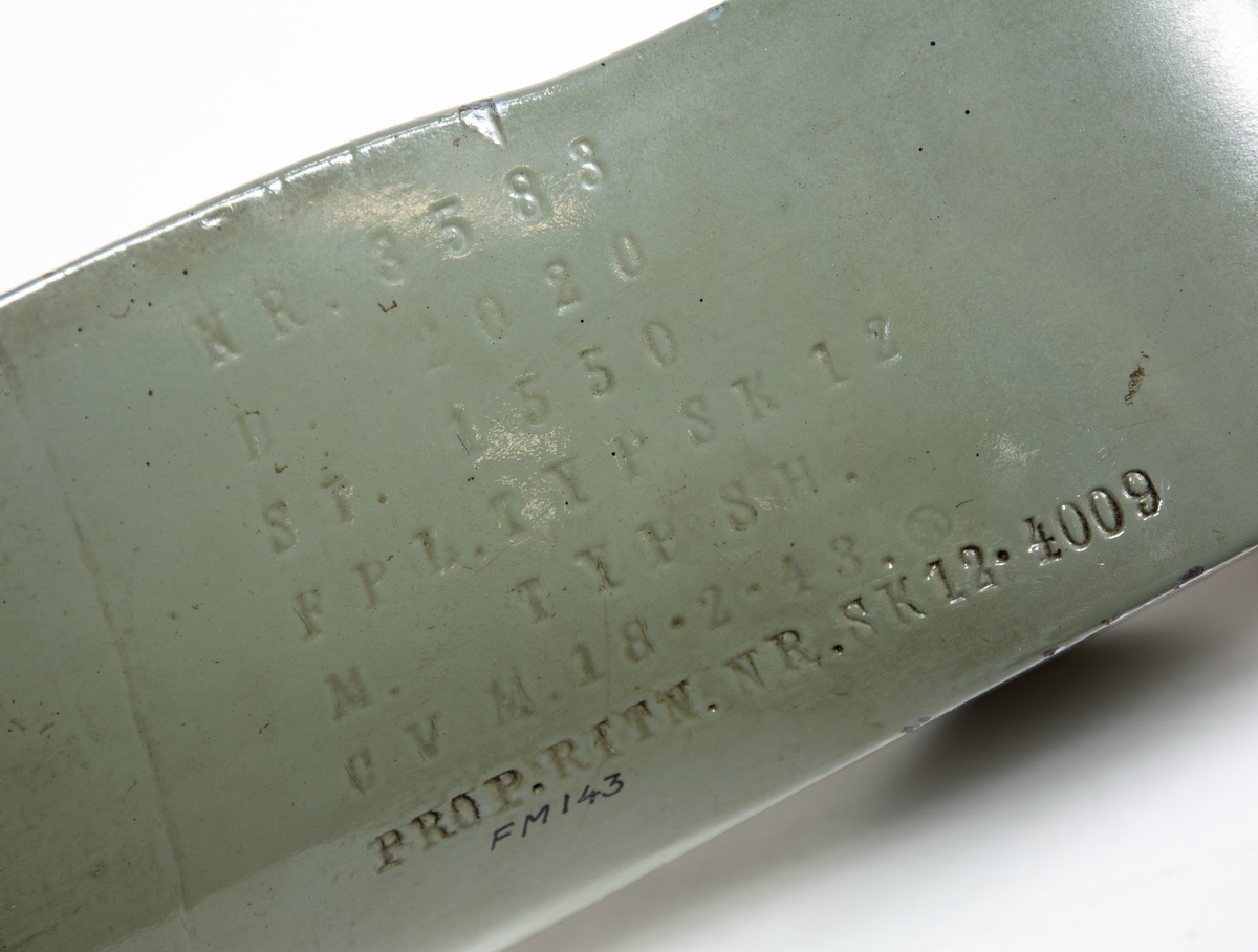 Tvåbladig träpropeller till SK 12. Propellern är målad grå och har skoning på bladen. Baksidan av propellerbladen är bruna. 
Propellern ligger i en trälåda. På locket står det att den tillhör SK 12/70.