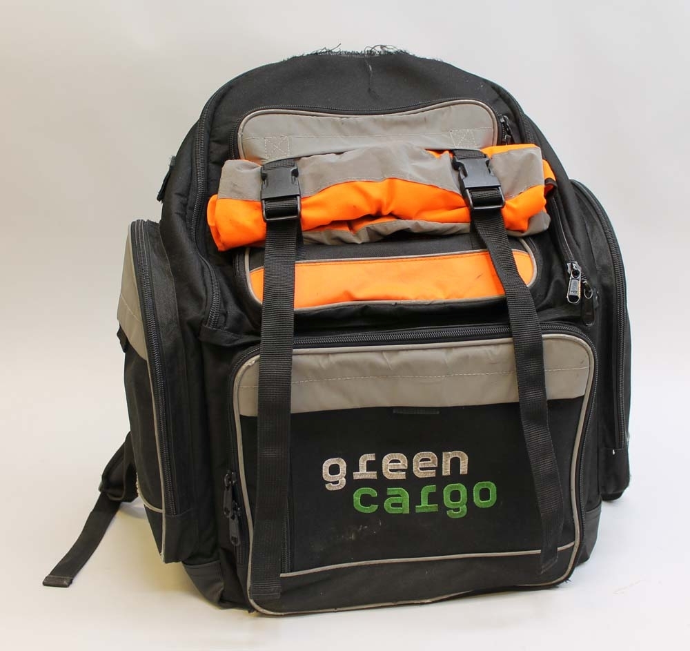 Svart ryggsäck med reflexer och ett fält med orange varseltextil. På framsidan är det broderat ett gult ånglok och "GÖRAN ENQVIST ESKILSTUNA" i rött samt "green cargo" i vitt och grönt. Ryggsäcken har två sidofack på vardera sida och fyra fack framtill samt diverse mindre fack inuti de två större främre facken såsom hållare för pennor, mobiltelefon, kort och dylikt. Huvudfacket har en vadderad avskiljare för t.ex. en laptop.