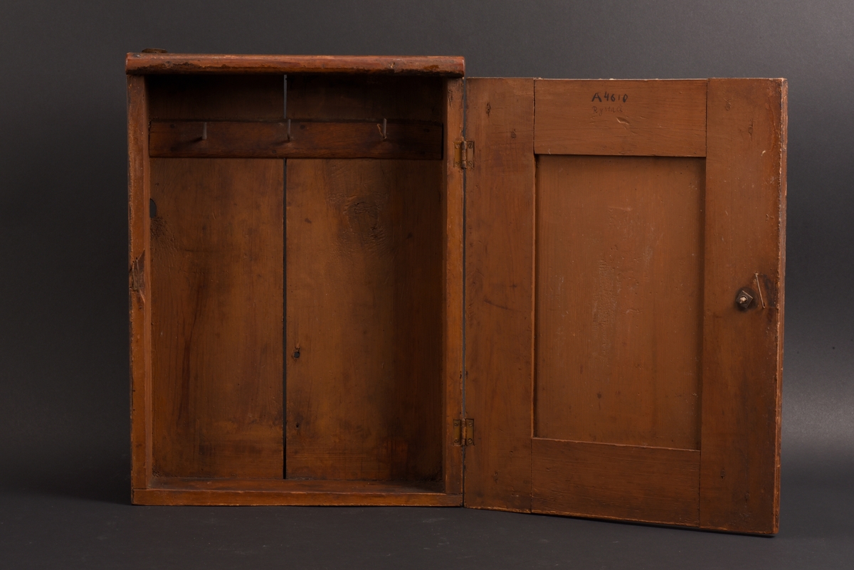 Rektangulärt nyckelskåp med vänsterhängd dörr av furu. På skåpsdörren är det en utsnidad nyckel. Skåpets utsida är målat i brun marmorering. Inne i skåpet tre böjda metalltenar för att hänga nycklarna på.