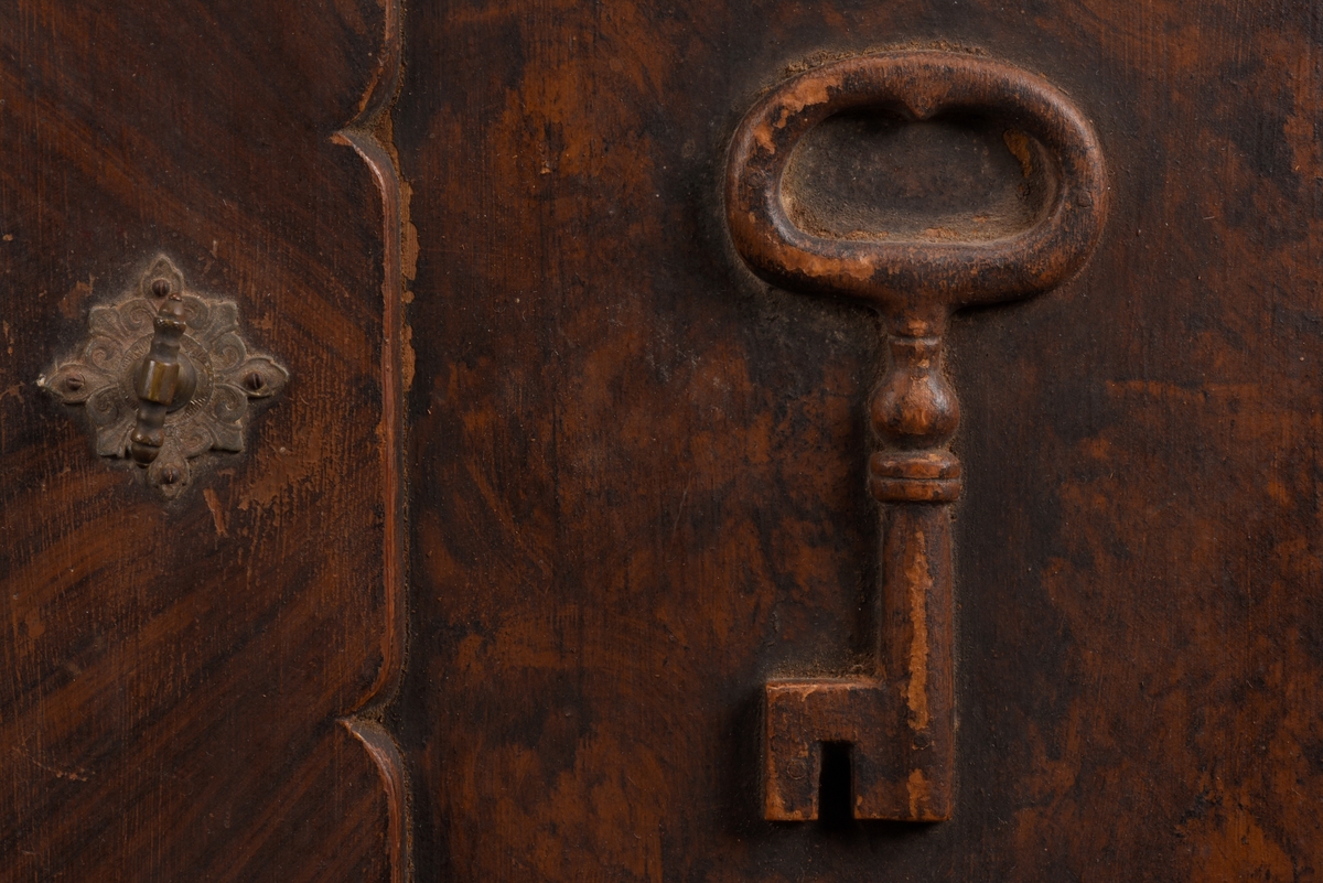 Rektangulärt nyckelskåp med vänsterhängd dörr av furu. På skåpsdörren är det en utsnidad nyckel. Skåpets utsida är målat i brun marmorering. Inne i skåpet tre böjda metalltenar för att hänga nycklarna på.