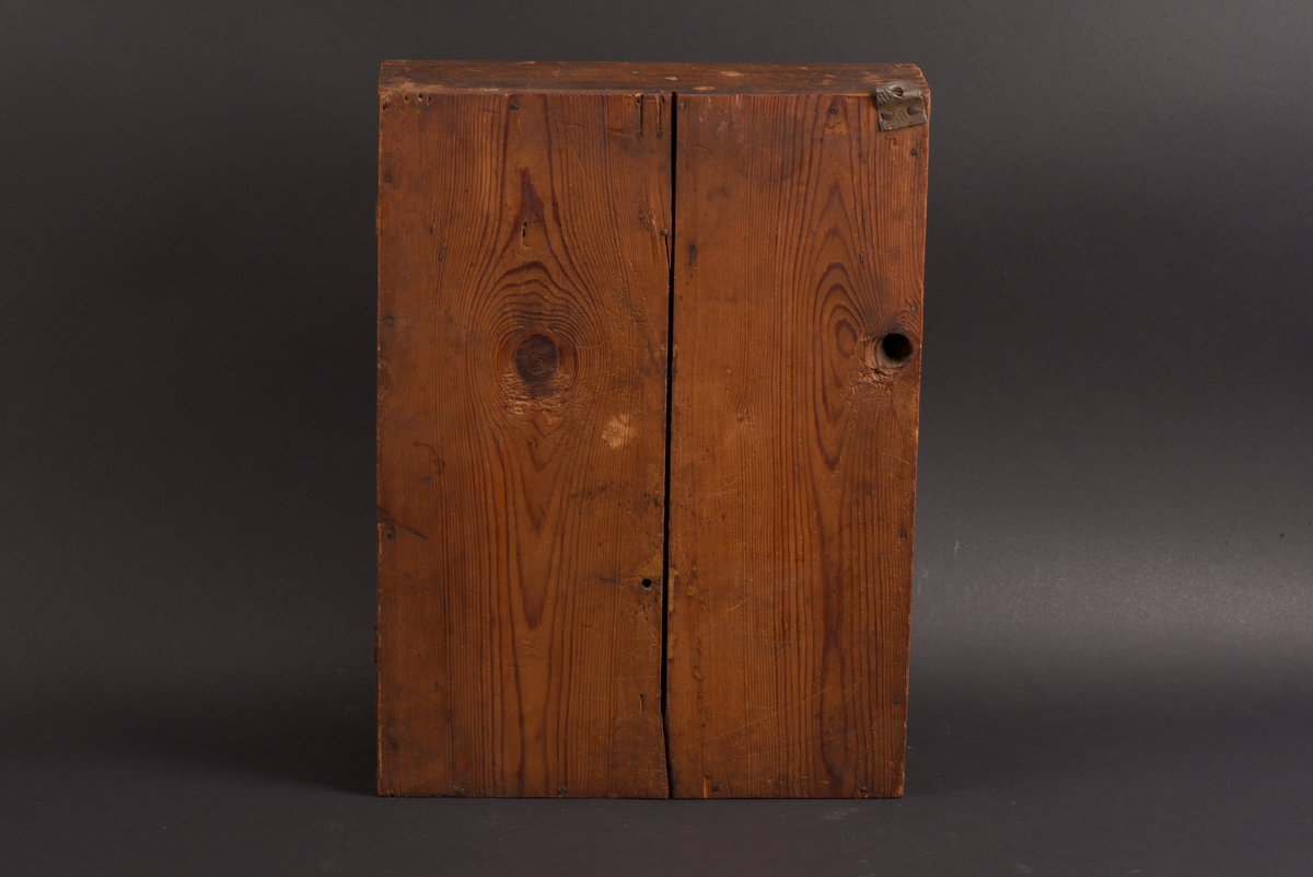 Rektangulärt nyckelskåp med vänsterhängd dörr av furu. På skåpsdörren är det en utsnidad nyckel. Skåpets utsida är målat i brun marmorering. Inne i skåpet tre böjda metalltenar för att hänga nycklarna på.