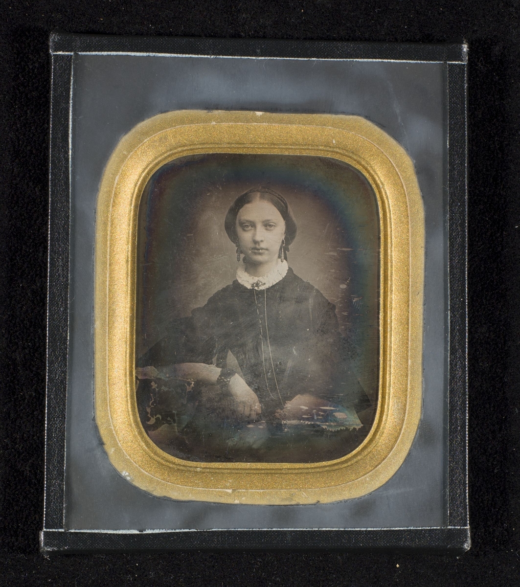 Daguerreotypi av dame sittende ved et bord.