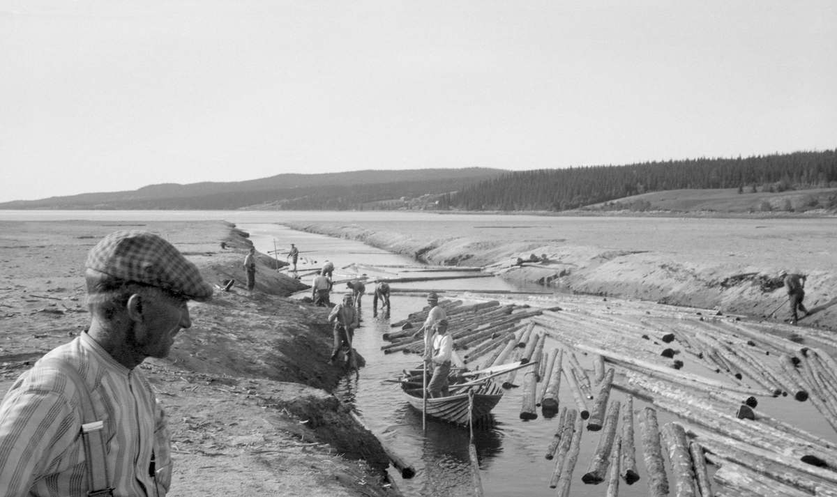 Kanalen som danner utløp var Vesle-Osen lengst sør i Osensjøen mot sjølve sjøen i 1942.  Fotografiet er antakelig tatt fra vegbrua ned mot fløterne, som er i virksomhet både i og langs kanalen, der det flyter mye tømmer. Sentralt i bildet er en robåt med et par fløtere i.  Ellers ses en rekke arbeidskamerater langs kanalens bratte, sandete bredder.  En fløter med rutete sixpenecelue betrakter virksomheten fra en posisjon lengst ned i venstre hjørne av bildeflata. 

Kanalen mellom Osensjøen og Vesle-Osen var for øvrig et vanskelig sted å fløte tømmer, blant annet fordi skiftninger i strømningene i sjøen kunne drive tømmeret sørover igjen.