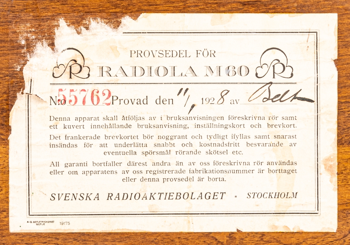 Batteridriven 2 rörs radioapparat. Lådan av svart och brunt trä. 2 par hörlurar. Diverse sladdar. På lådans sida en metallbricka "SVENSKA RADIOAKTIEBOLAGET STOCKHOLM" På undersidan provsedel med text: "...RADIOLA M60...".