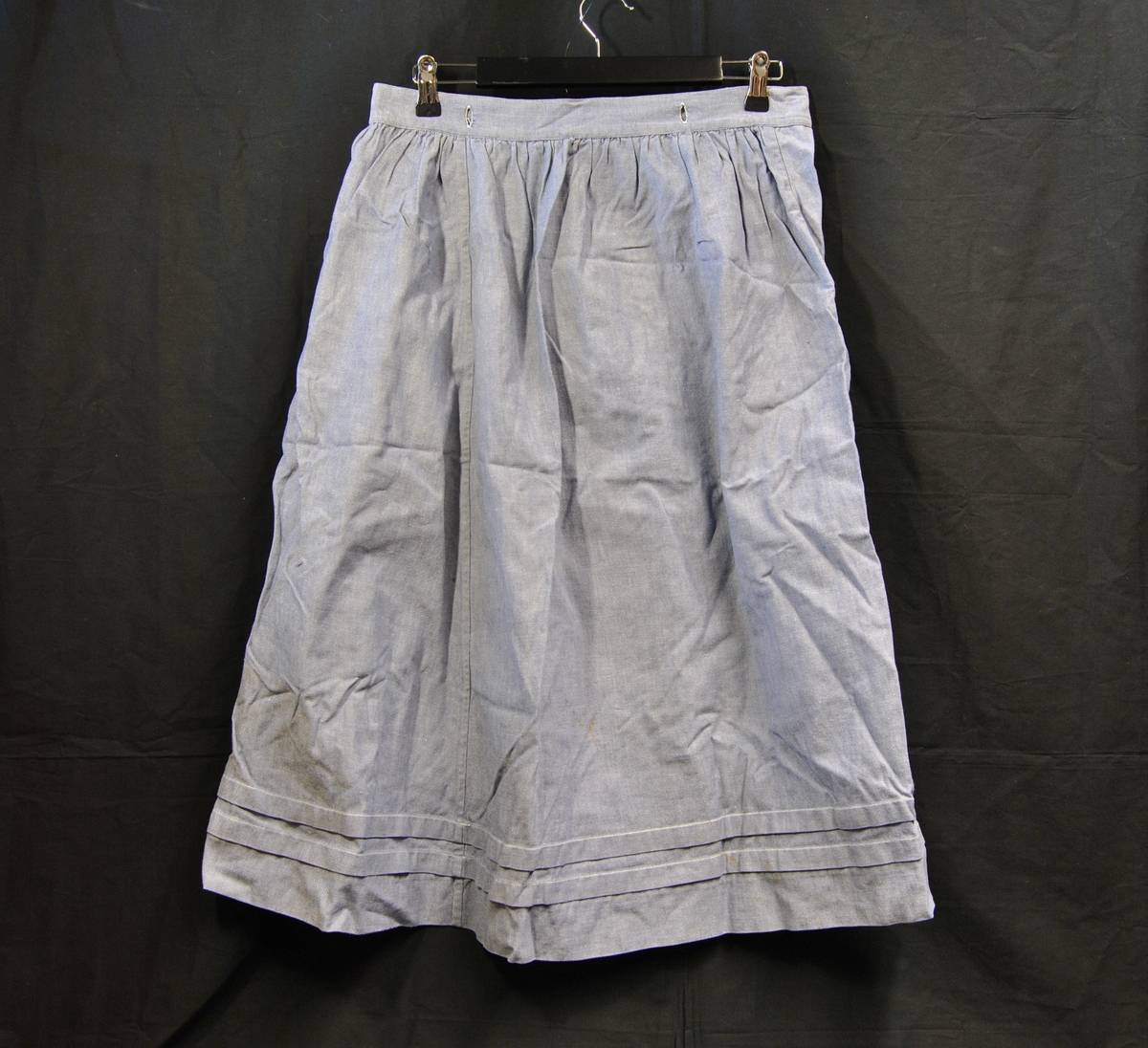 A-formet skjørt med hempe og knepping bak. Knappehull rund linningen.