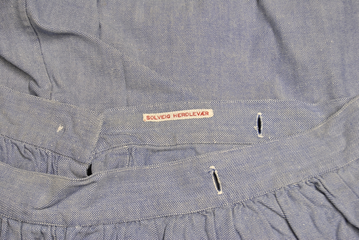 A-formet skjørt med hempe og knepping bak. Knappehull rund linningen.