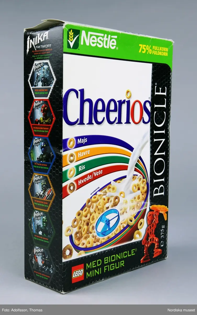 Rektangulär flingförpackning av kartong med heltäckande färgillustrationer. På framsidan ett fat med flingor och mjölk samt bild på en leksak (samlarfigur) som ligger i paketet. I skrift står "Cheerios [...] 75 % fullkorn" samt "Bionicle [...] Med bionicle mini figur" och Legos logotyp. På motsatta sidan, samt på ena kortsidan, presenteras de medföljande samlarfigurerna med instruktioner om hur man leker och tävlar med dem. Se länkad fil.