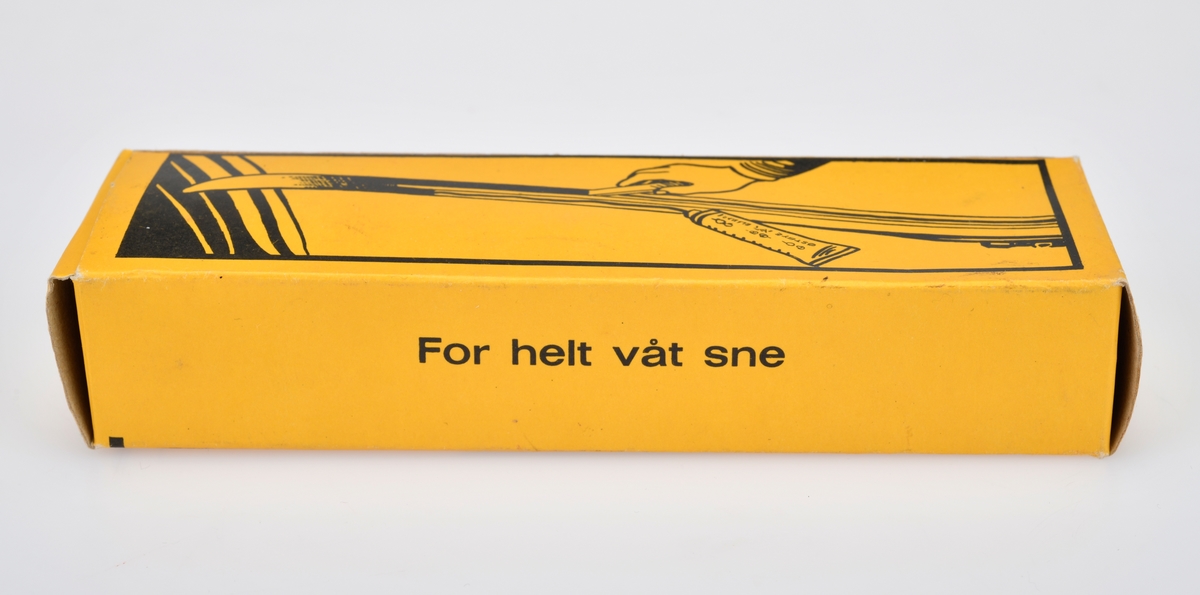 En eske med en tube med skiklister av typen Østbye Klister. Esken er av papp og er gul med svart tekst og dekor. For tekst se "Påført tekst/merker". På forsiden er det tegning av to skiløpere - en i motbakke og en i utforbakke. Det er også tegninger av medlajer/utmerkelser klisteret har vunnet. På baksiden er det en tegning som viser hvordan man skal påføre klisteret. Esken kan åpnes i begge kortendene. Tuben er av metall og korken er av svart plast. Tuben er gul med svart skrift/dekor. På forsiden er det tegning av to skiløpere - en i motbakke og en i utforbakke samt medaljer/utmerkelser klisteret har vunnet. På baksiden står det "For helt våt sne" på 10 ulike språk. I esken er det også en trespatel til å påføre klisteret med. Den er terhvit og laget av ubehandlet tre.