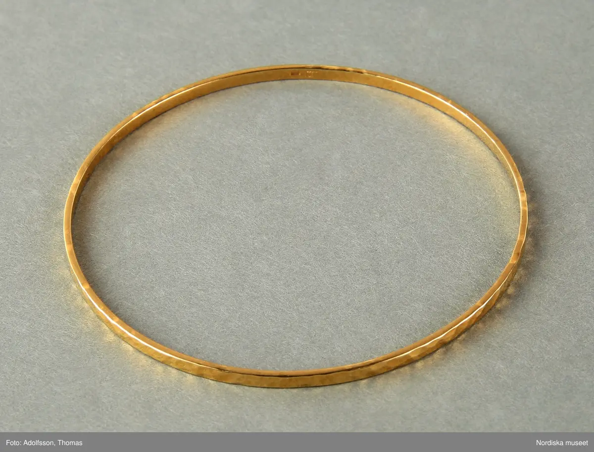 Armringar  i guld,  5 st = 2 st släta utan dekor (a-b), 1 st med dekor med tvärgående räfflor (c) och  2st  med hammrad dekor (d-e).
Samtliga armringar är stela samt utan öppning. Stämplade BJA 585. 


/Cecilia Wallquist 2019-02-15