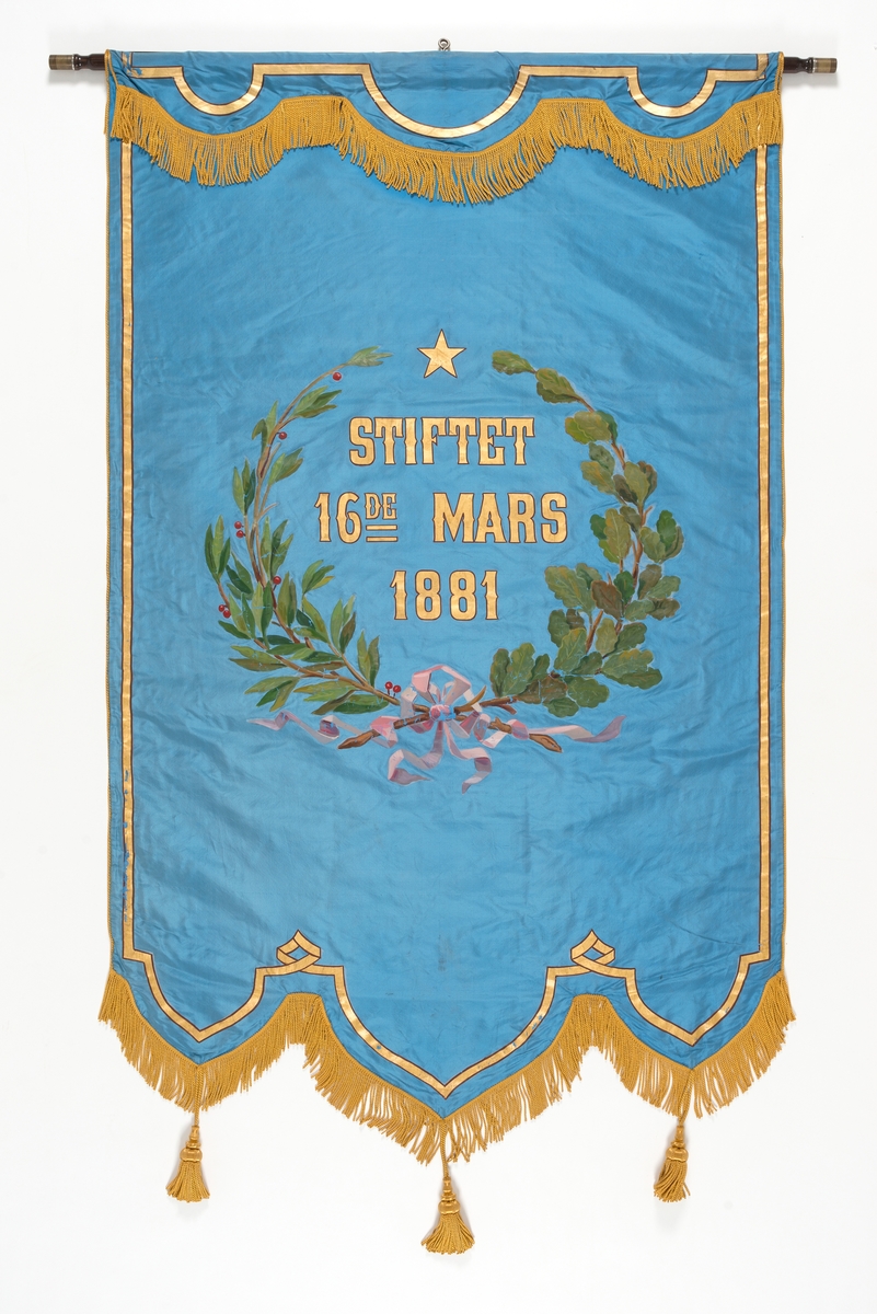 Forside: Kvinne og mann sitter i landskap med bautastein mellom seg. Han er omgitt med verktøy til å hogge i stein. På steinen er følgende innskripsjon: , "DNGTO Et kykkeligt Norge ort maal"., , Bakside: Krans av eikeblader og laubærblader.