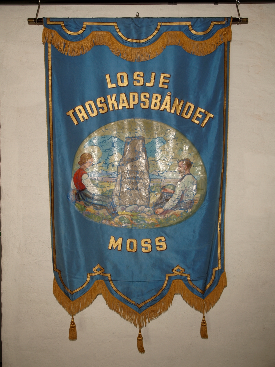 Forside: Kvinne og mann sitter i landskap med bautastein mellom seg. Han er omgitt med verktøy til å hogge i stein. På steinen er følgende innskripsjon: , "DNGTO Et kykkeligt Norge ort maal"., , Bakside: Krans av eikeblader og laubærblader.