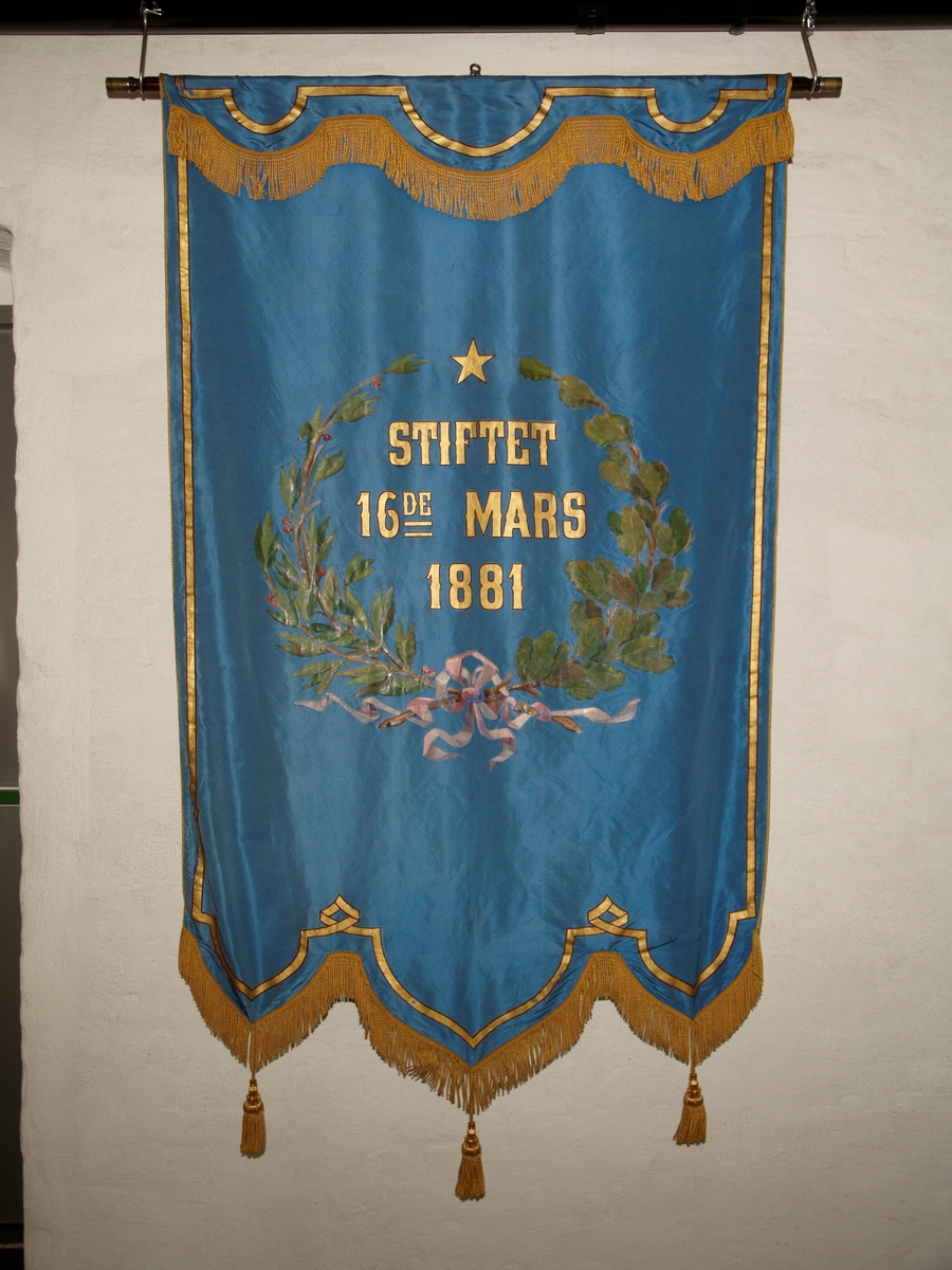 Forside: Kvinne og mann sitter i landskap med bautastein mellom seg. Han er omgitt med verktøy til å hogge i stein. På steinen er følgende innskripsjon: , "DNGTO Et kykkeligt Norge ort maal"., , Bakside: Krans av eikeblader og laubærblader.