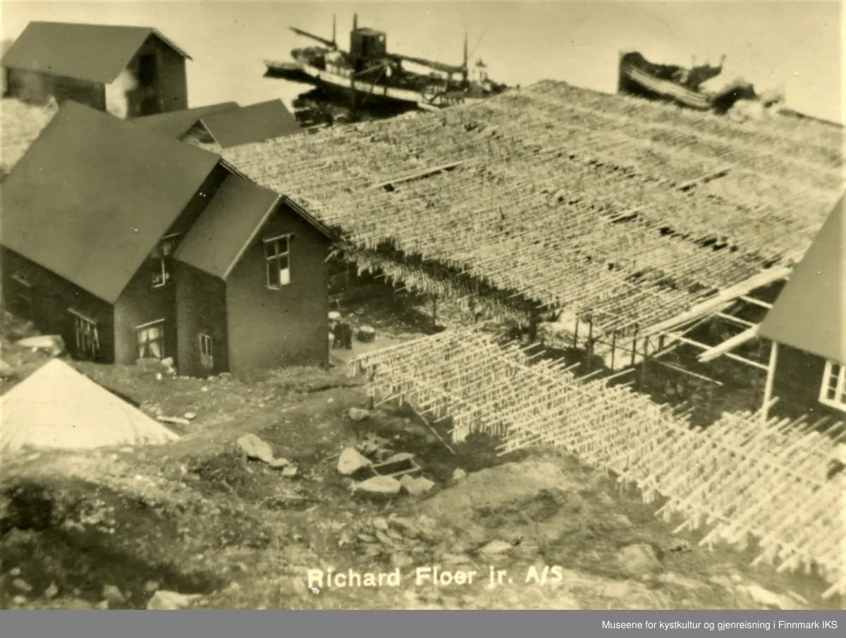 Postkortmotiv. Storbukt. Floerbruket med fiskehjeller, bebyggelse og skip ved kaia. Ca. 1935.
