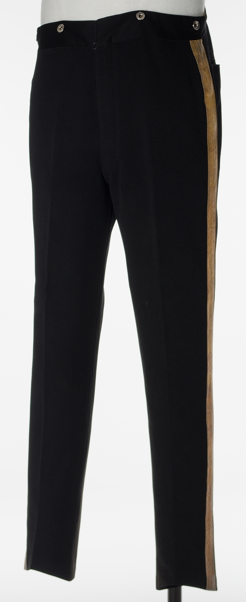 Enkeltspent jakke til uniform i sort ull. Åtte tekstiltrukne knapper i fronten. Kraven er opprettstående og kan lukkes med en metallhekte.  Skuldrene har påsydd hempe på hver side av kragen og hver skulder er dekorert med et 9,5 cm langt vevd, sølvbånd, festet i hver ende vertikalt på skulderen. Baksiden har splitt opp til livlinjen med lommer på hver side inn fra splitten og tre par tekstiltrukne knapper. Nederst på ermene er det utenpåsydd mansjett med spiss og to tekstiltrukne. Innvendig er jakken helforet med sort bomullsfor og vattering i overdelen. Gult fôr i ermene. Opphengshemper i nakken. 

Bukse i mørk blå ull med to lommer bak. Vevd gullbånd i sidene. Gylf lukkes med metallhekte og fire knapper (ant. i tre). Åtte metallknapper utvendig på linning. Hvitt fôr med smale striper i rødt, lyseblått og lysegrått i linning. Sandfarget fôr i lommene.