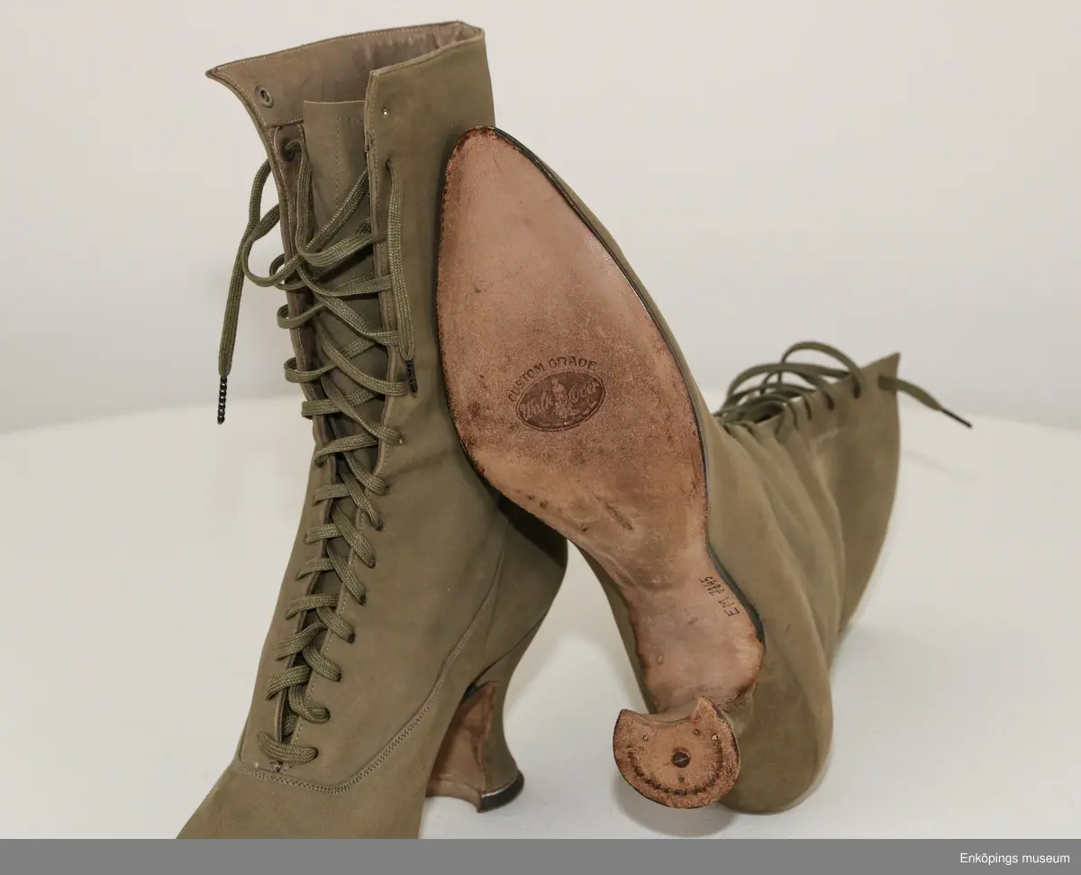 Grönbeige snörkänga för dam av mocka med taxklack.
Tillverkare: Walk Over. Märke: Custom Grade.
Inköpta i Amerika av givarens far Bele Nyström 1916/17. Storlek 38.