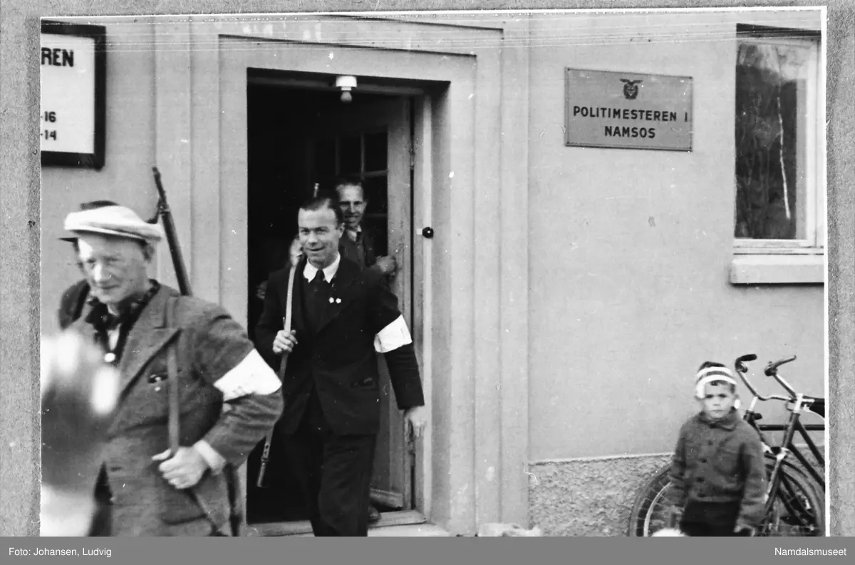 Namsos sentrum, Skolegata, Hakligården, 8. mai 1945. Nye polititjenestemenn går ut i arbeid med geværet over aksla.