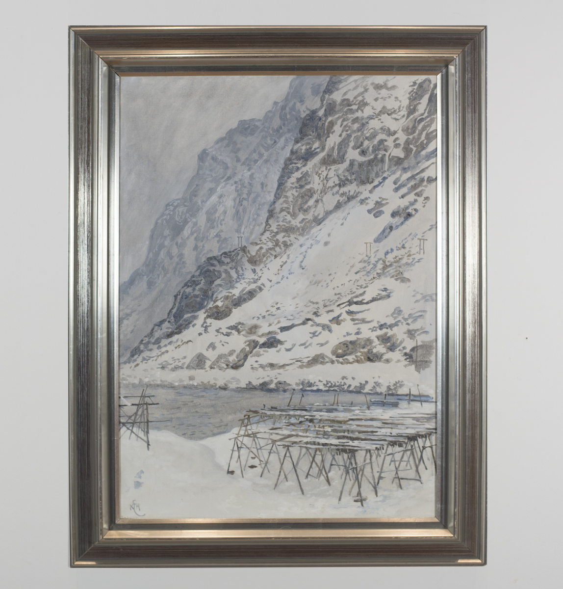 Vinterlig landskap med bratte fjellsider og hav. Fiskehjell sees i forgrunnen. 
